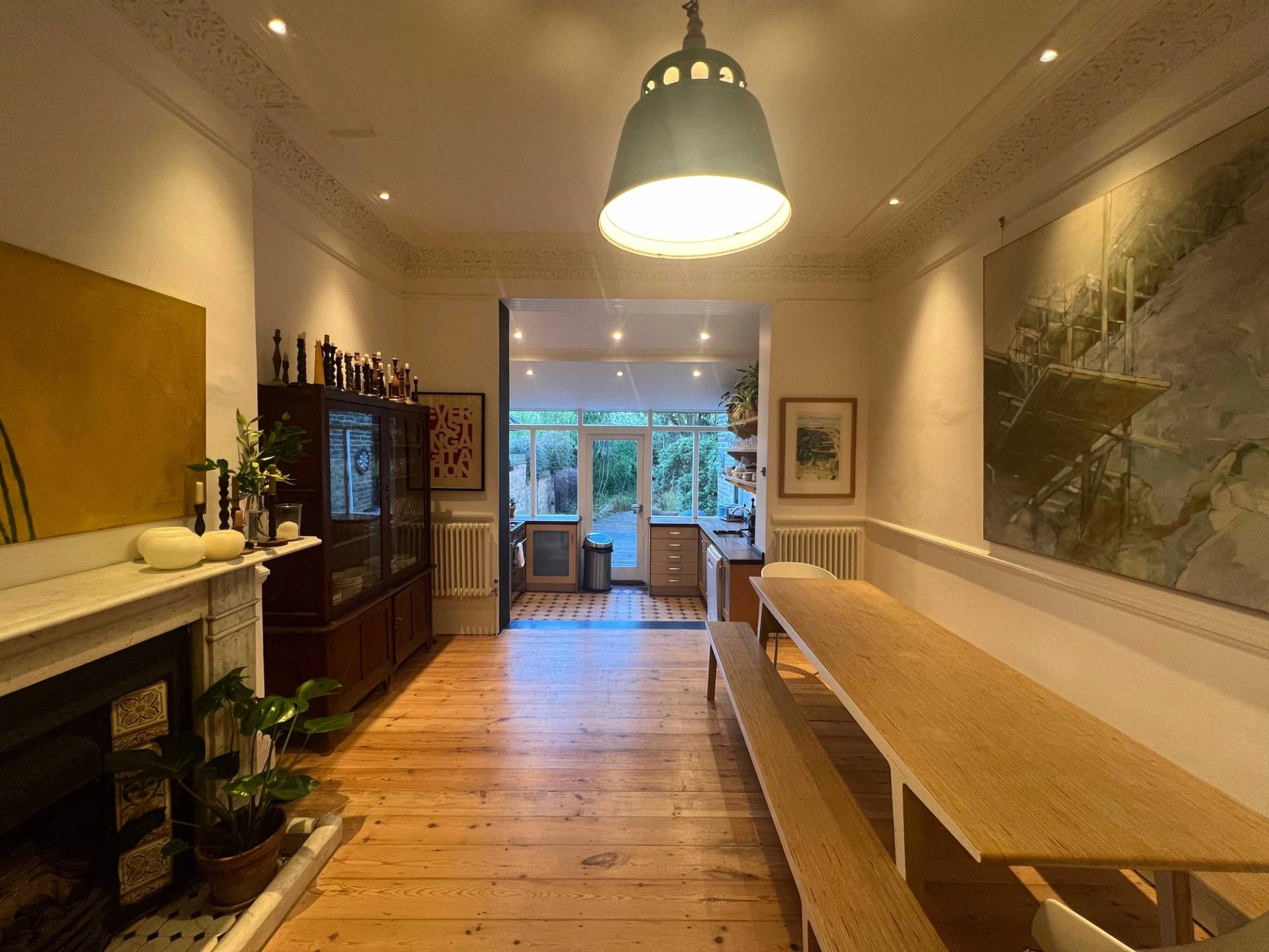 Long wooden dining bench and dining table set against original timber floors and period fireplace details in SE5, Love Locations.