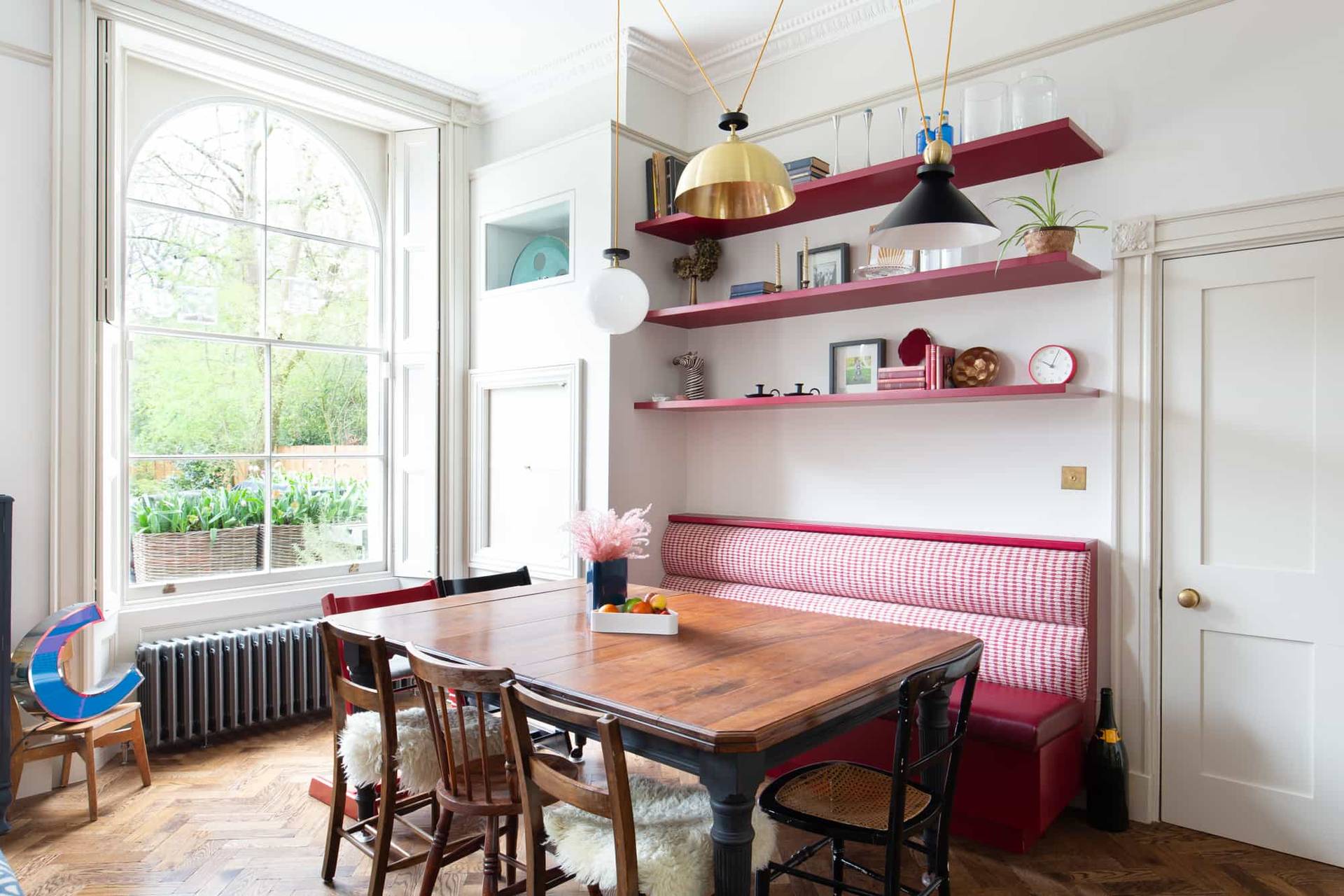 Dining room location in Camberwell, SE5 featuring burgundy leather banquette seating, wooden dining table, and open shelving via Love Locations.