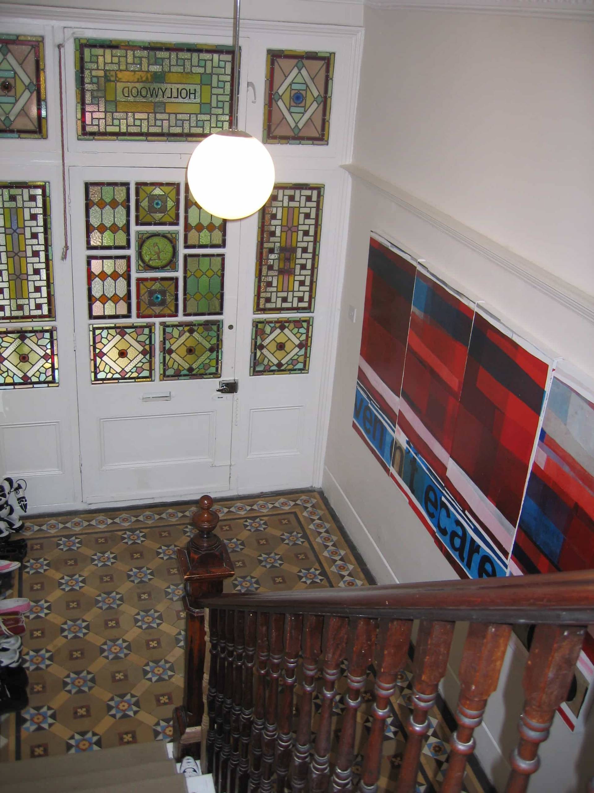 High-angle view down a grand Victorian staircase showing stained glass transom panels and mosaic floor tiling, Love Locations SE5.