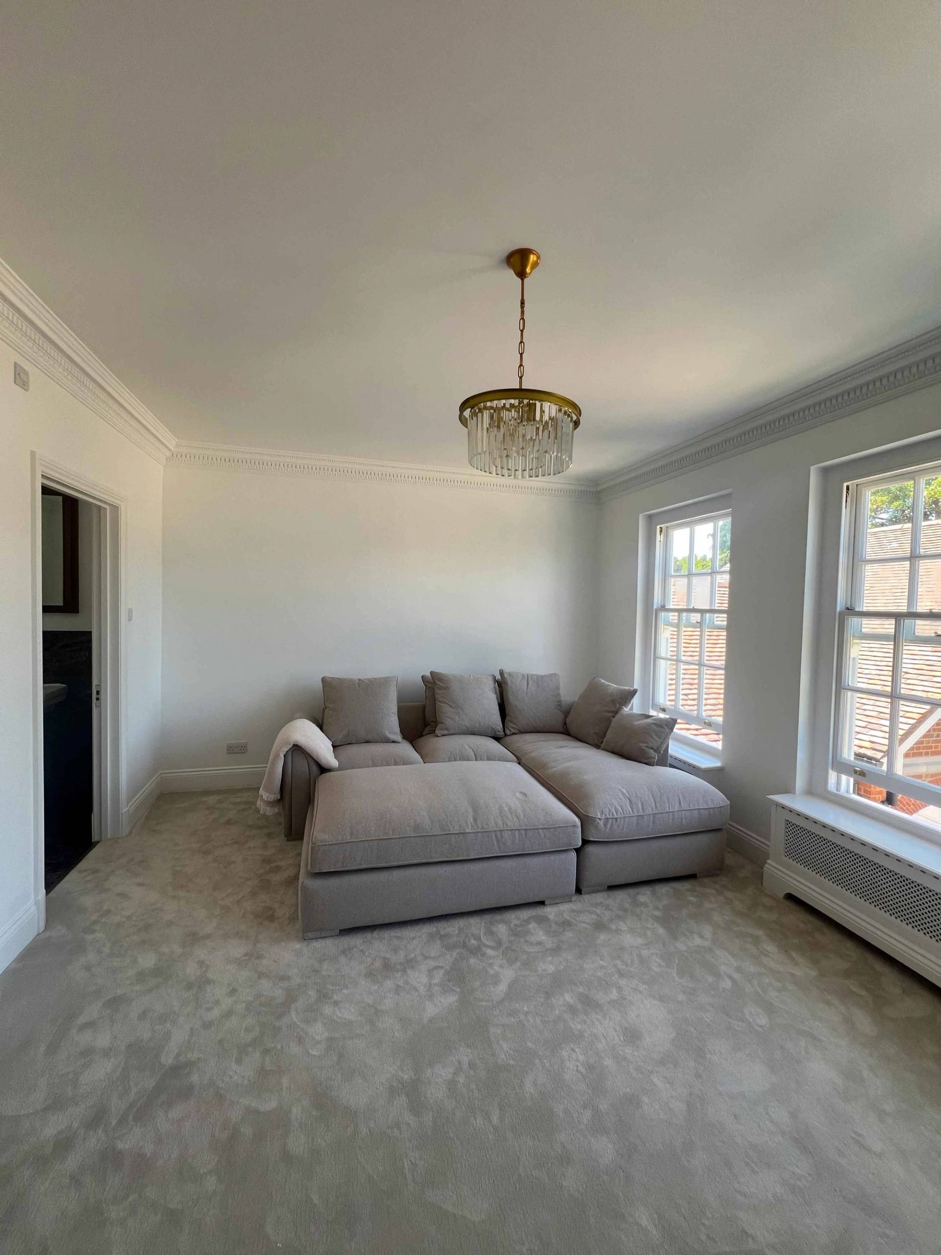 Family media lounge with a modular grey sectional sofa, wall-mounted television, and sash windows, Love Locations BR7.