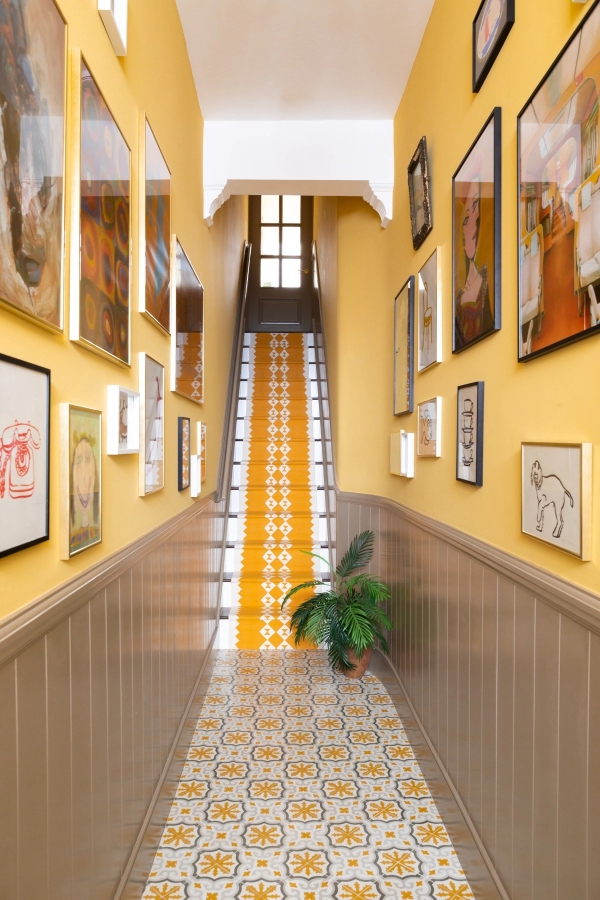 Grand hallway shoot location in Westminster London SW1V from Love Locations, featuring a gallery wall of framed art and a striking yellow-runner staircase.