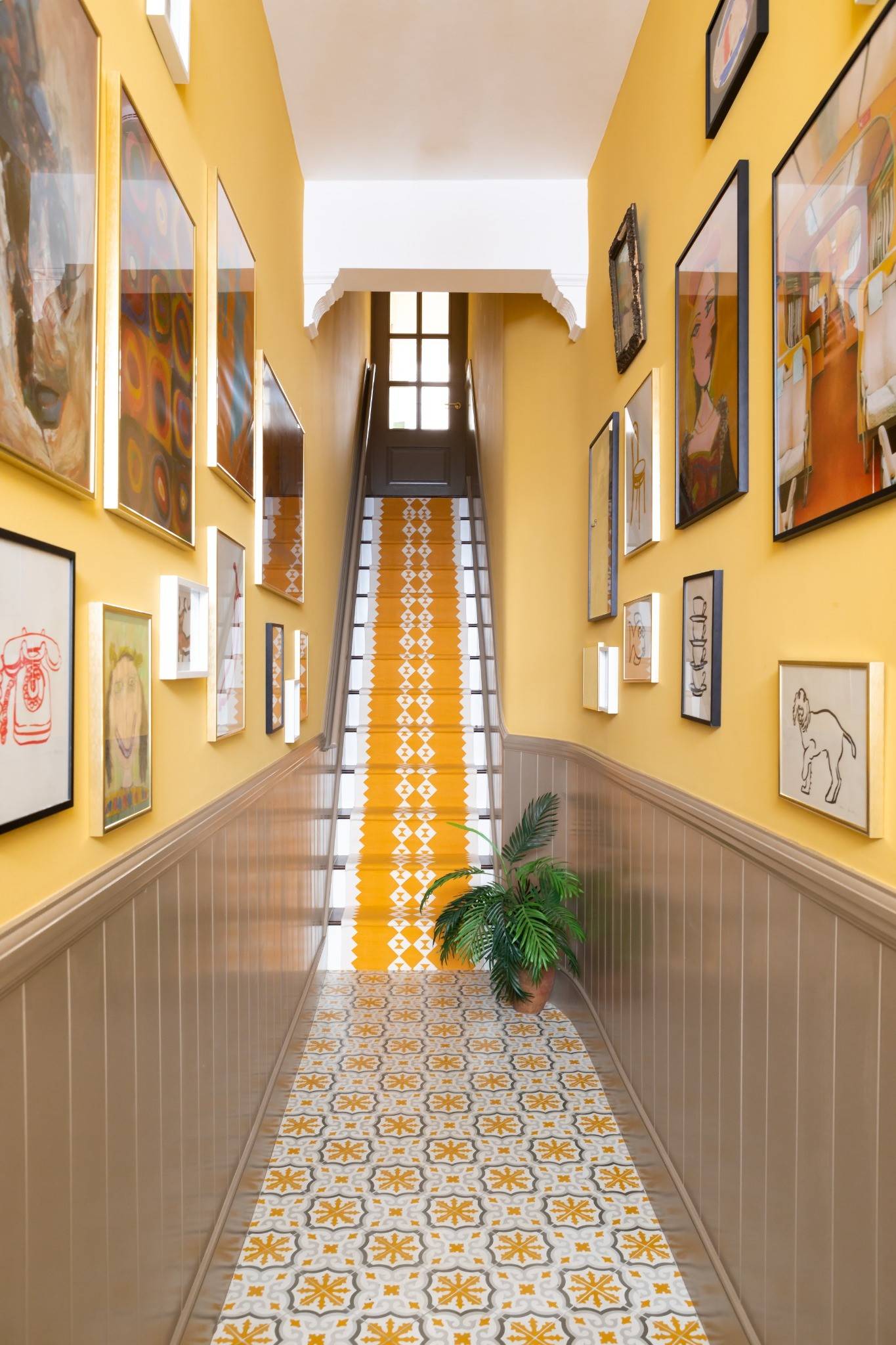 Grand hallway shoot location in Westminster London SW1V from Love Locations, featuring a gallery wall of framed art and a striking yellow-runner staircase.
