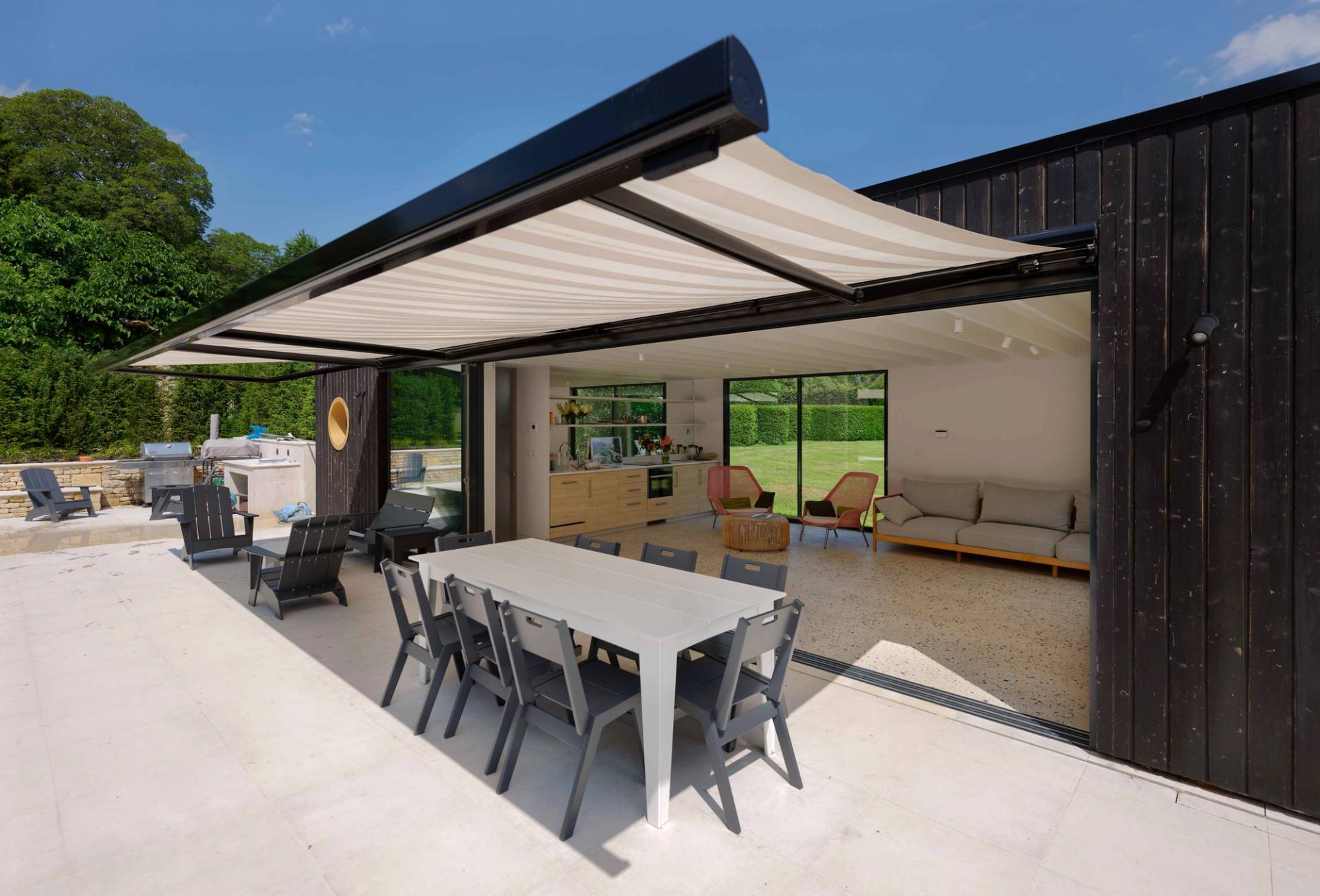 Poolside dining patio set under an open pergola extension with long dining table and chairs, Love Locations OX7.