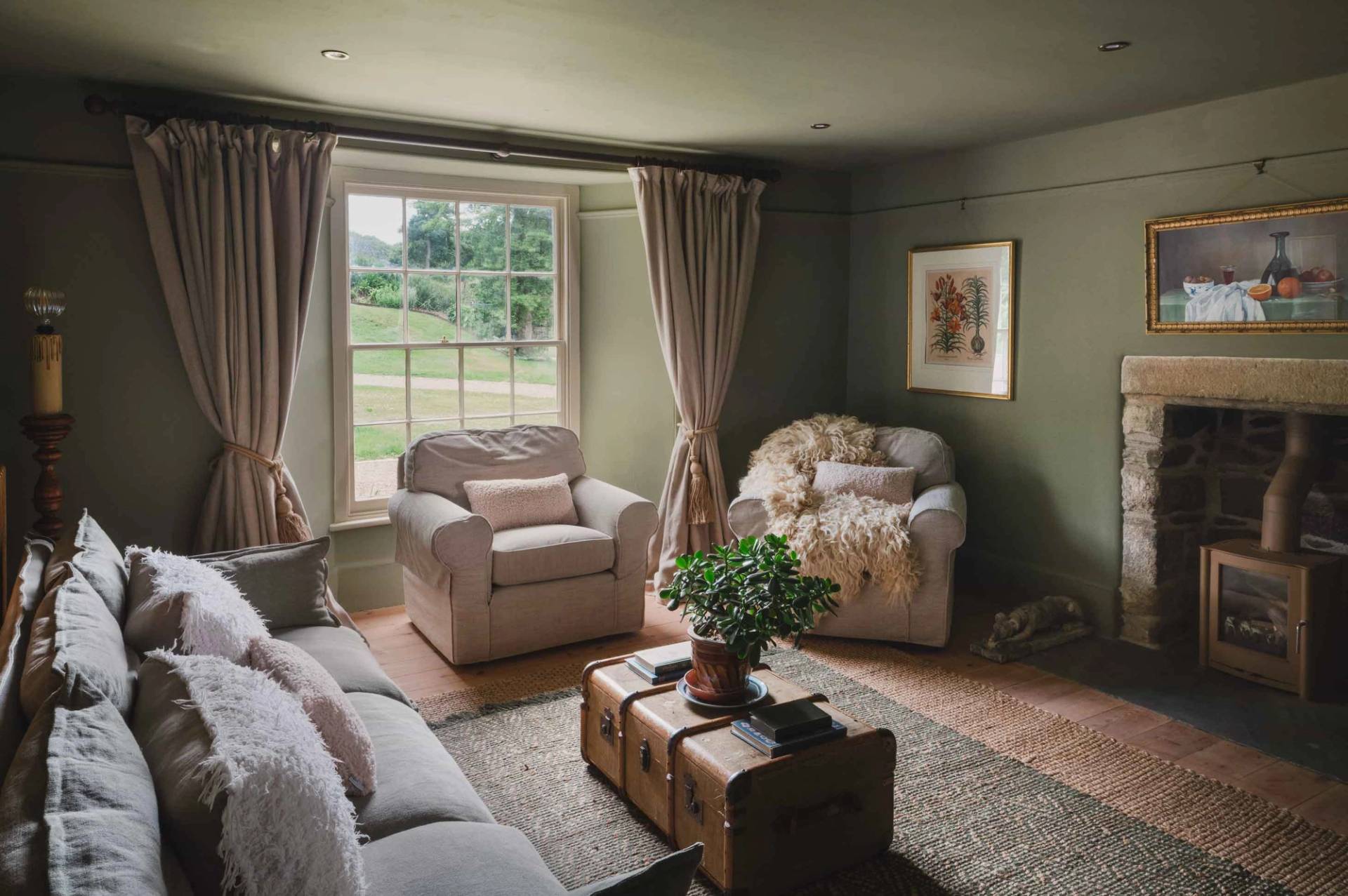 Cozy period living room film location in Newquay Cornwall TR8 by Love Locations, with dark green walls, a plush sofa, neutral armchairs, and sash windows.