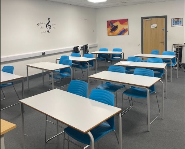 Love Locations school music room Reading RG30: Clean classroom interior with neat tables, blue chairs, and musical notes graphic on the wall, ideal for youth productions and lifestyle photography.