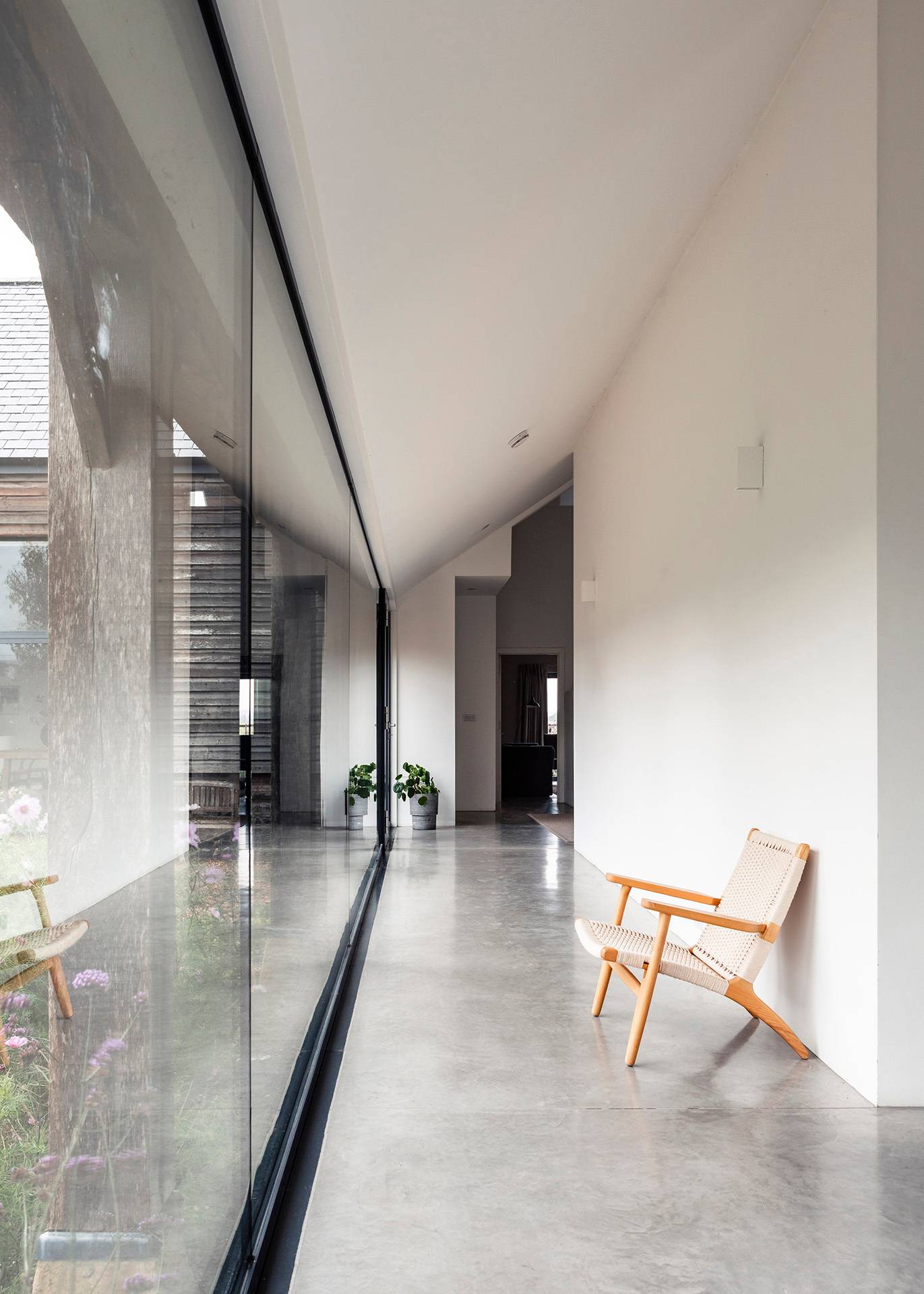Architectural glass link corridor in Wiltshire, SN8 featuring floor-to-ceiling glass windows and polished concrete floors, Love Locations.