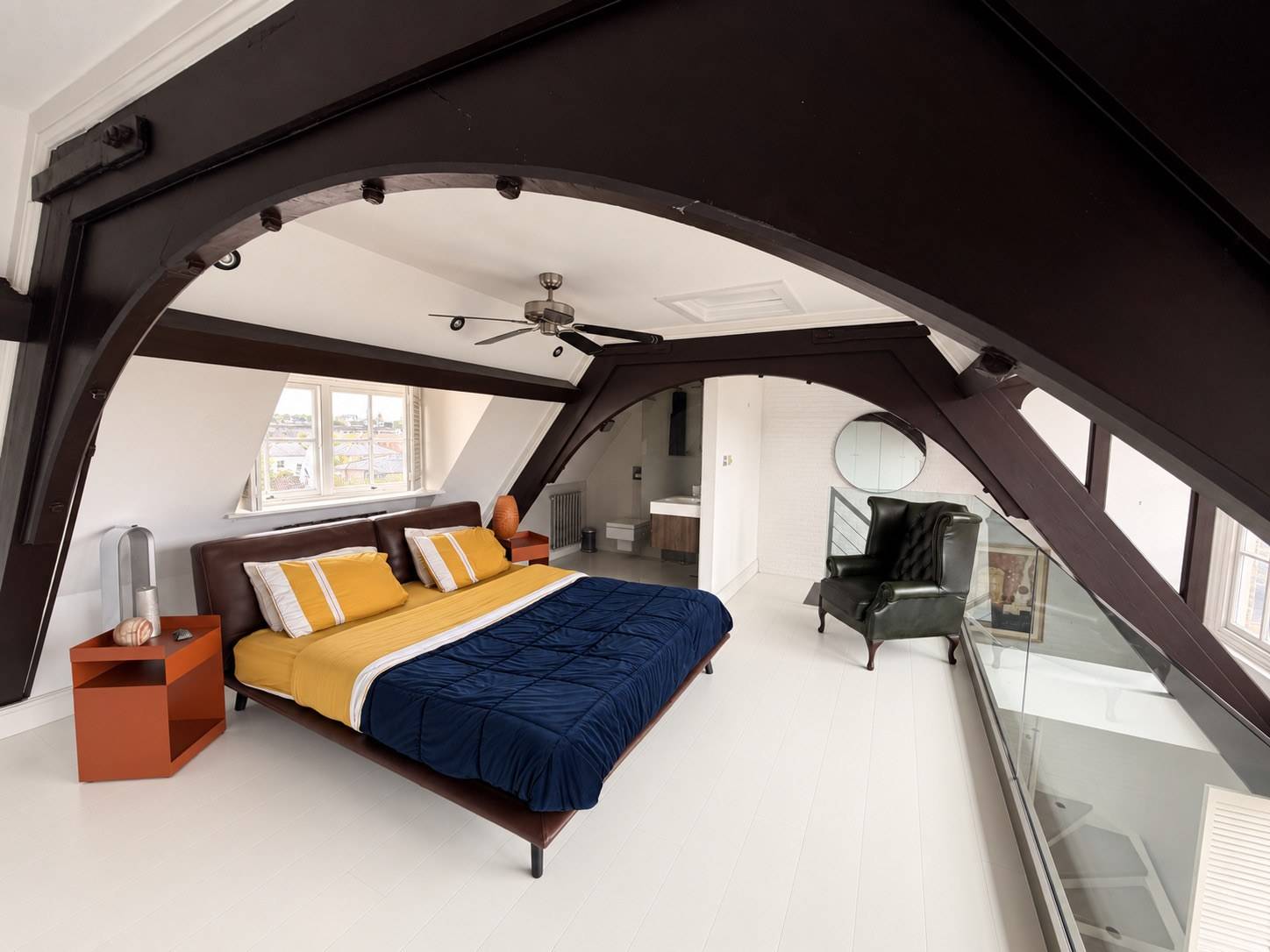 Atmospheric master bedroom set beneath dramatic exposed dark timber roof trusses in a Brixton SW4 penthouse location, available through Love Locations.