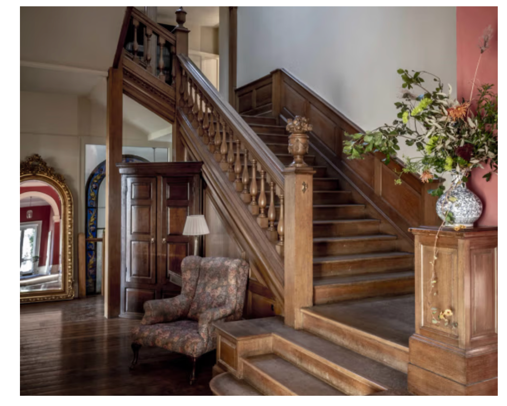 Grand wooden staircase at Keythorpe Hall featuring original timber panelling, heritage architecture and a statement entrance hall.