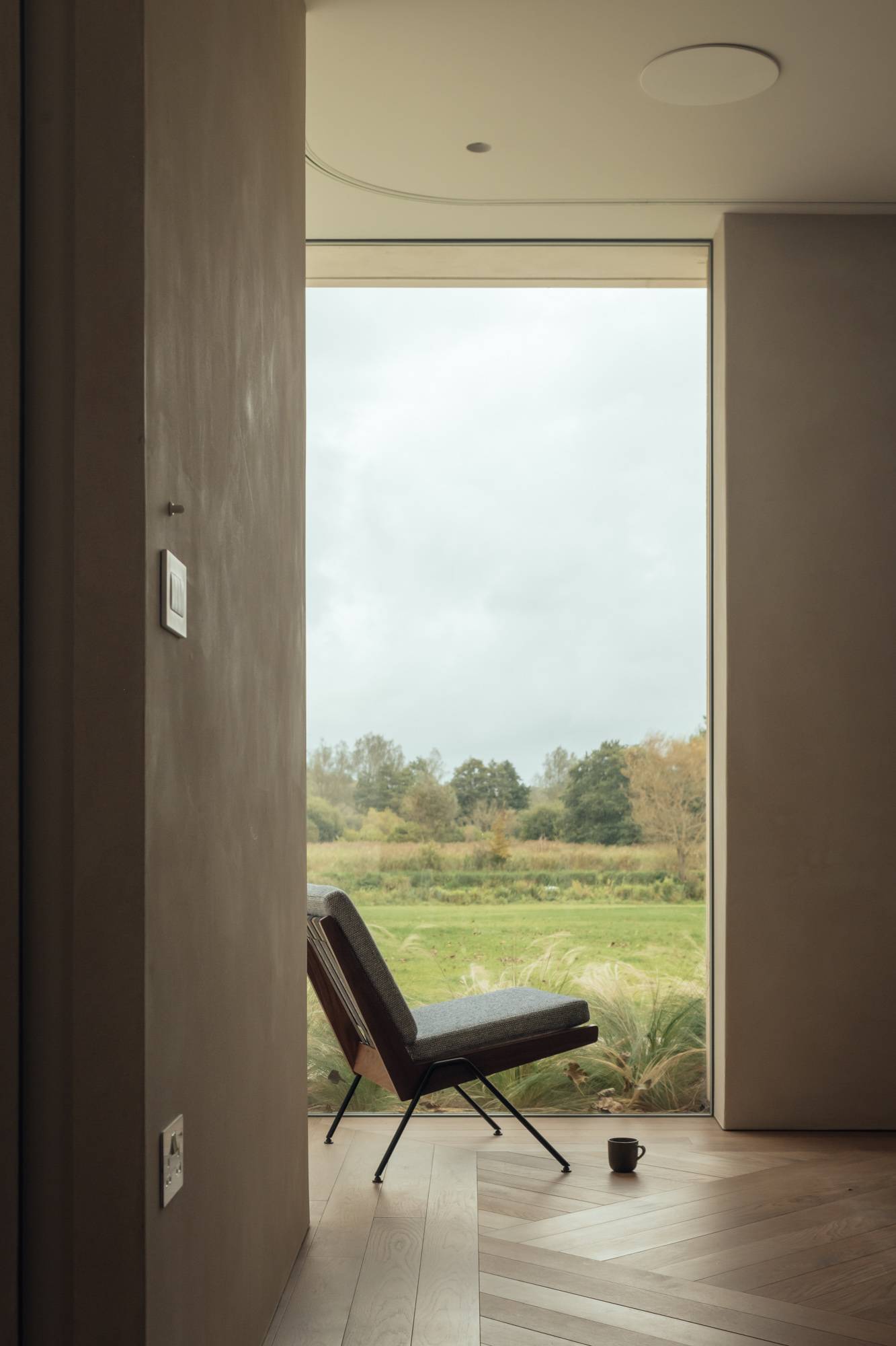 Floor-to-ceiling glass doorway framing scenic green fields and natural light in a Stockbridge location home, Love Locations SO20.
