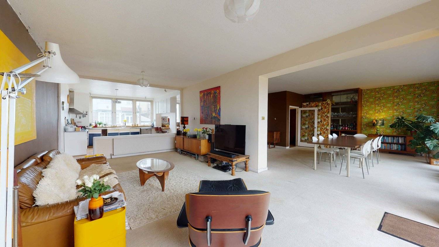 Open-plan 1970s living space transition showing carpeted floors, mid-century TV console, and retro artwork, Love Locations SW16.