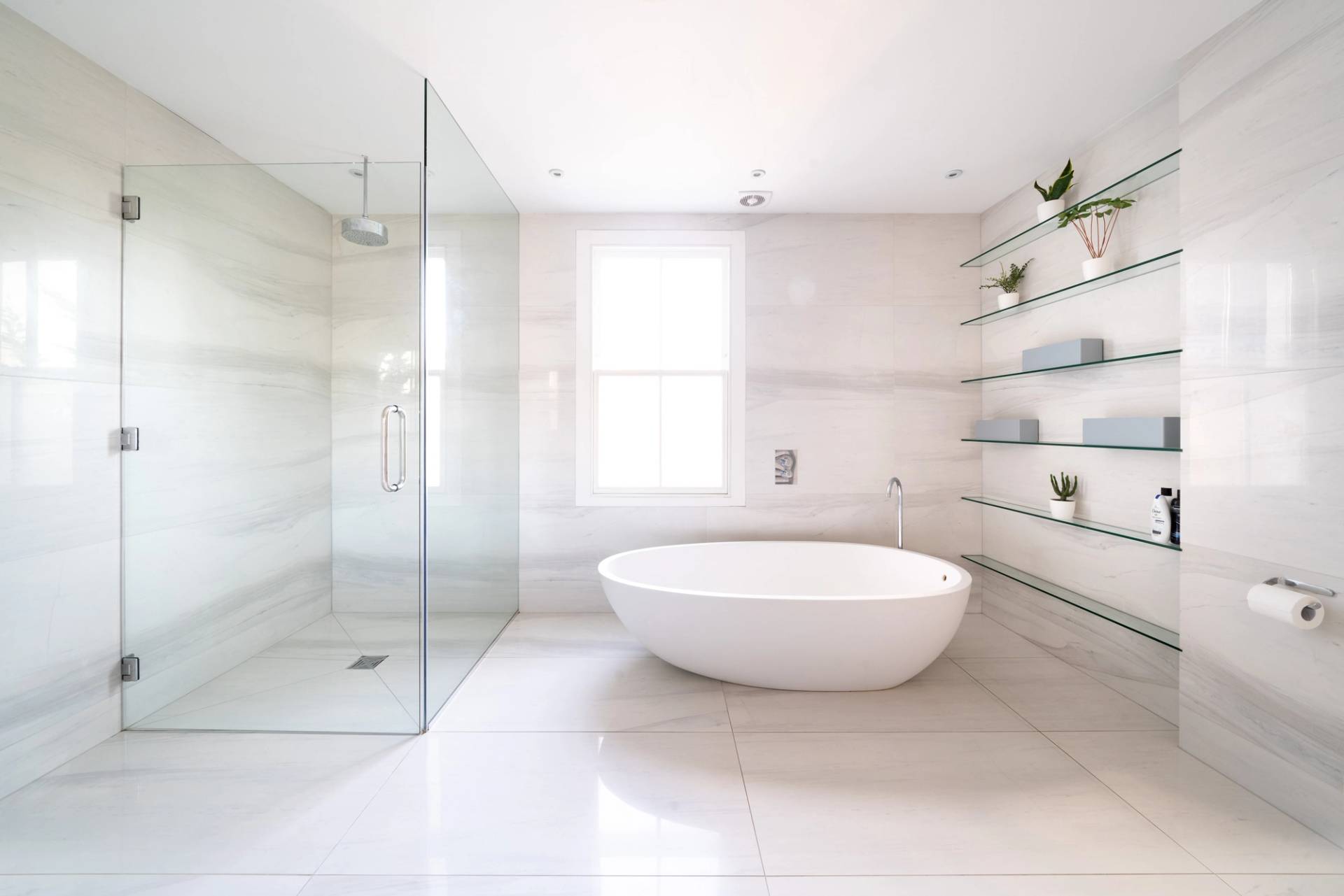 Contemporary master bathroom featuring a freestanding oval bathtub, walk-in glass shower, and white tiles, Love Locations SW6.