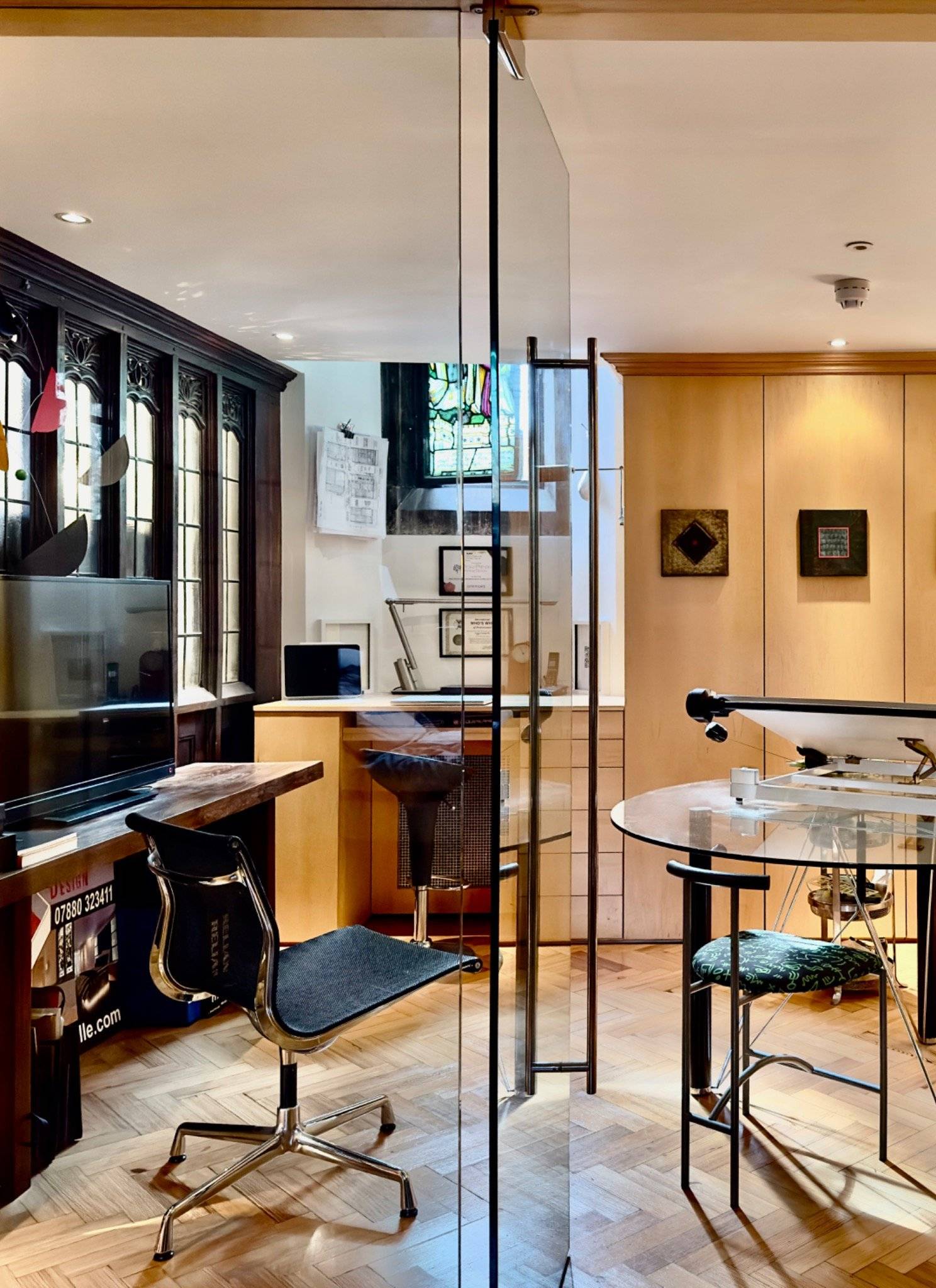 Upper gallery office space with fitted timber cabinetry and glass partition walls inside a chapel conversion in Oval SE5 by Love Locations.
