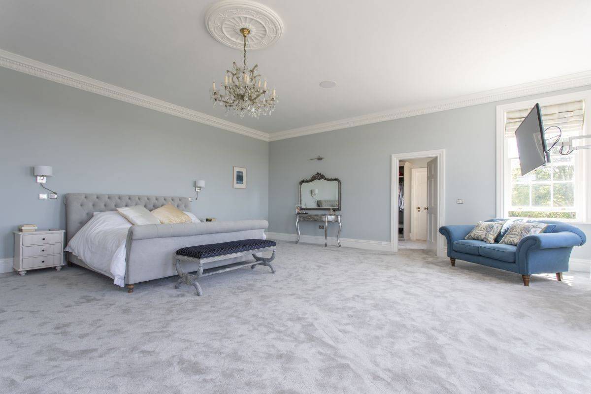 Spacious master suite with a luxury upholstered bed, plush grey carpet, and neutral walls for film set hire, Love Locations West Sussex.