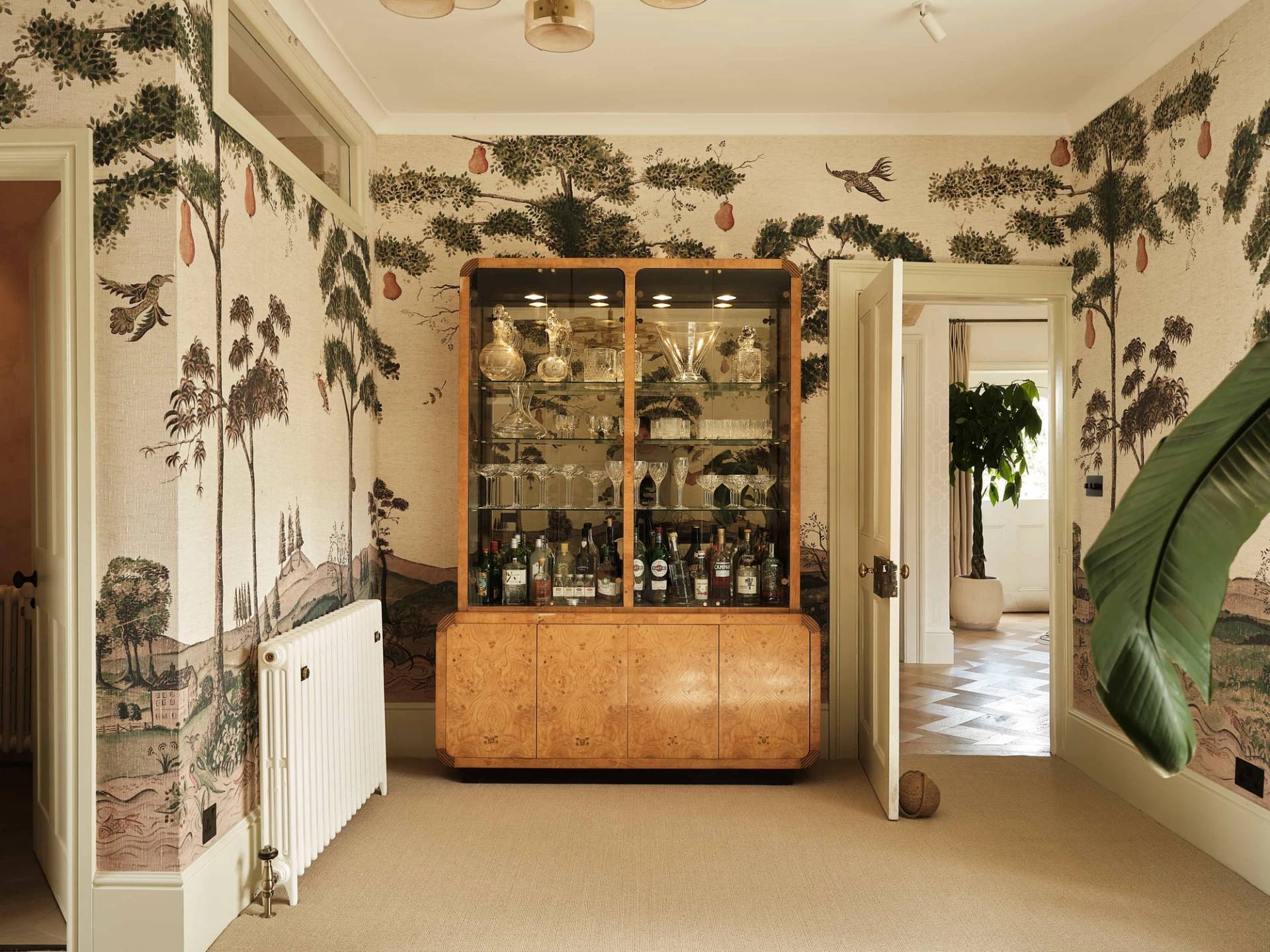 Formal dining space or reception hall showcasing scenic forest wall mural wallpaper and a burr wood cabinet, perfect for high-fashion editorial photography, Love Locations OX7.