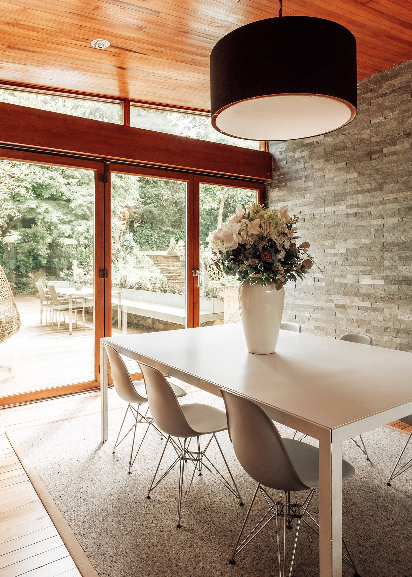 Spacious dining area oriented toward glass sliding doors that open out onto a sunlit wooden outdoor deck, Love Locations BR1.