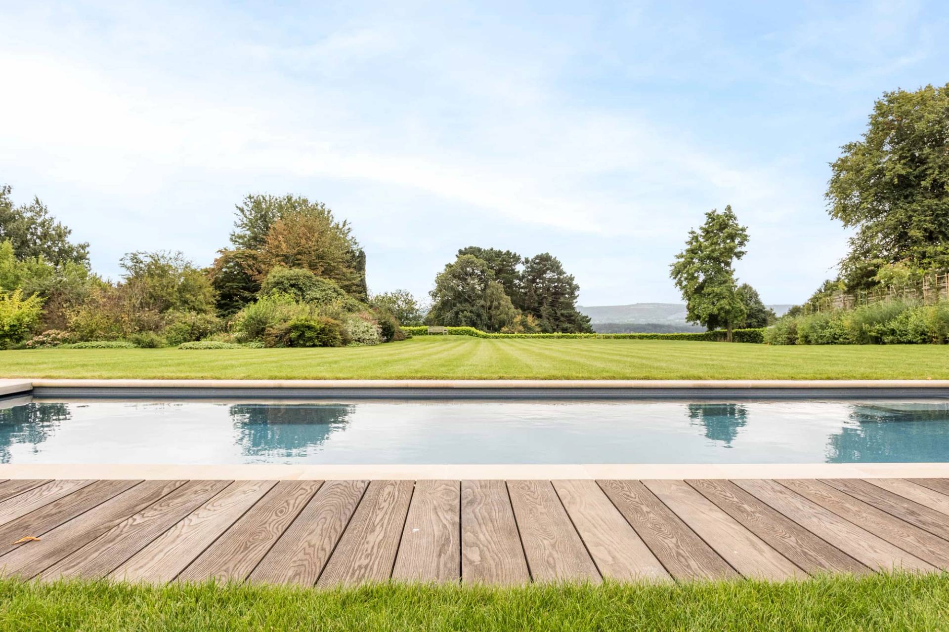 Luxury outdoor swimming pool shoot location in Petworth, GU28 featuring timber decking and expansive countryside views, Love Locations.
