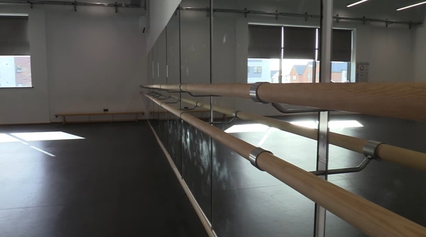 Love Locations dance studio shoot location Reading RG30: Close-up perspective of a wooden ballet barre running along a full-wall mirror, designed for fitness and dance performance lookbooks.