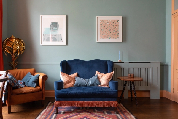 Cozy living room seating area for photoshoot hire in Westminster SW1V through Love Locations, showing a dark blue armchair, wood panelling, and framed artwork.