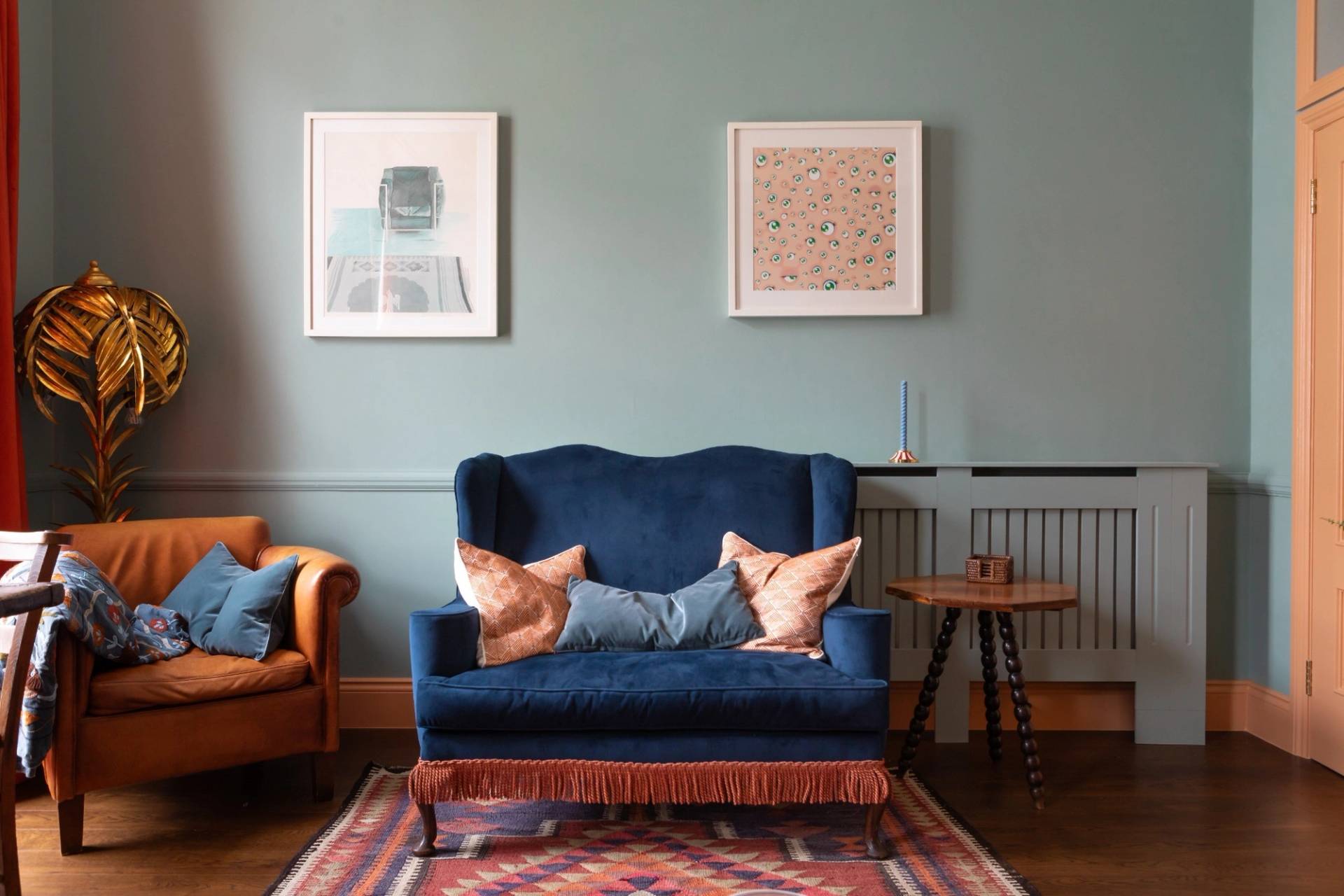 Cozy living room seating area for photoshoot hire in Westminster SW1V through Love Locations, showing a dark blue armchair, wood panelling, and framed artwork.