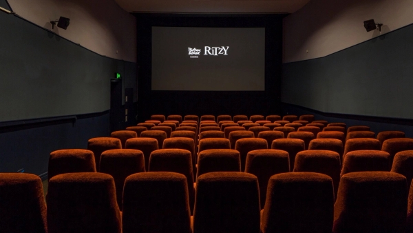 Straight-on view down the central aisle toward the illuminated projection screen displaying the Ritzy logo inside The Ritzy Screen 4 venue hire by Love Locations.