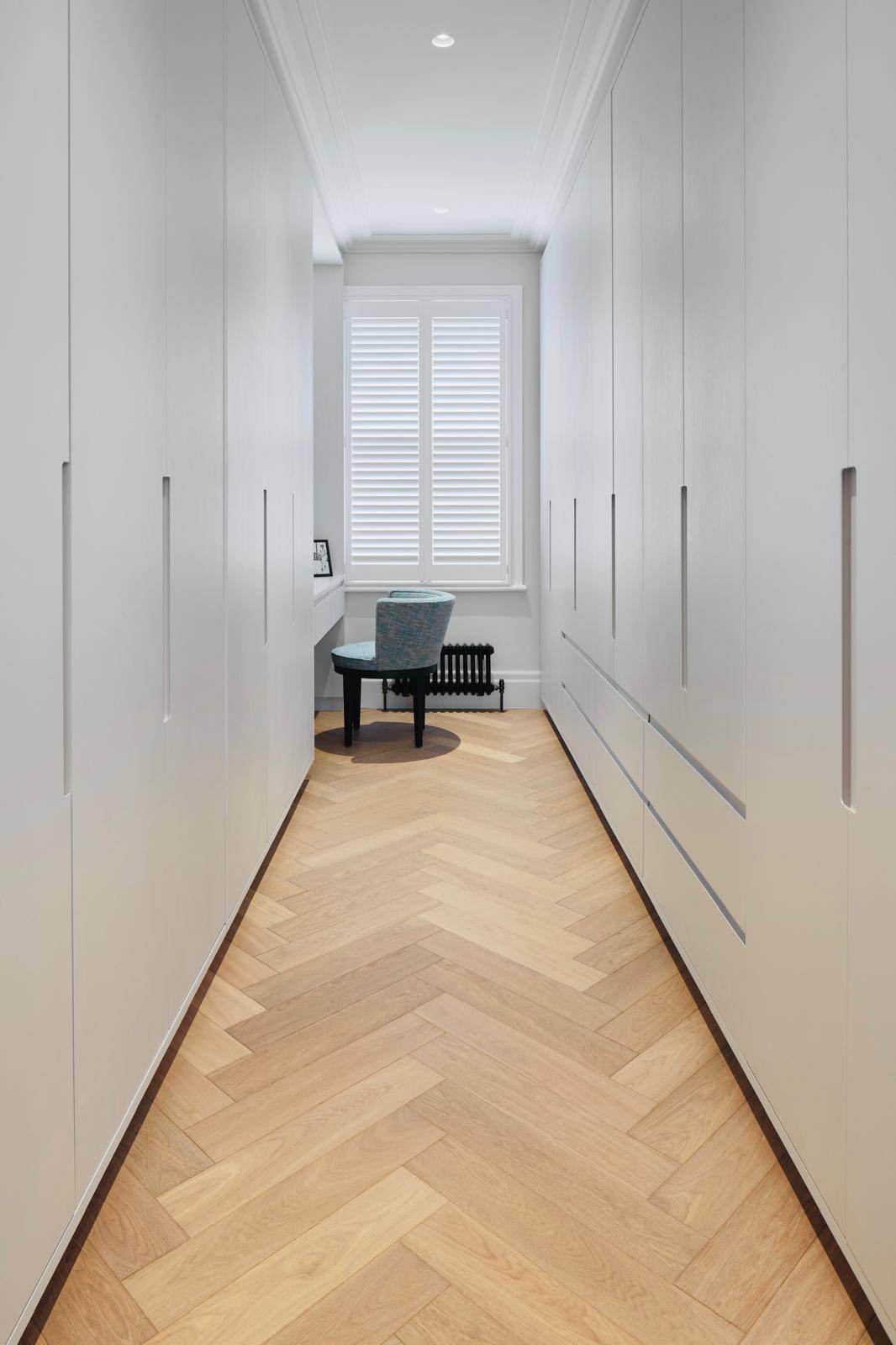 Dressing room hallway lined with sleek white built-in wardrobes and herringbone floors, Love Locations TW11.