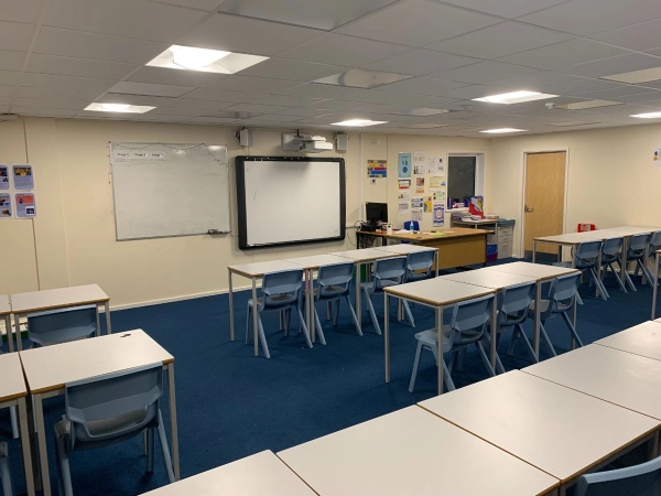 Love Locations modern classroom shoot space BS7: Clean secondary school classroom with a digital smartboard, whiteboard, and neat rows of desks, perfect for educational TV commercials.