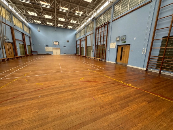 Love Locations commercial sports hall backdrop Cockfosters: Expansive indoor gymnasium showing side exit double doors and gymnastics climbing tracks, excellent for sports apparel branding.