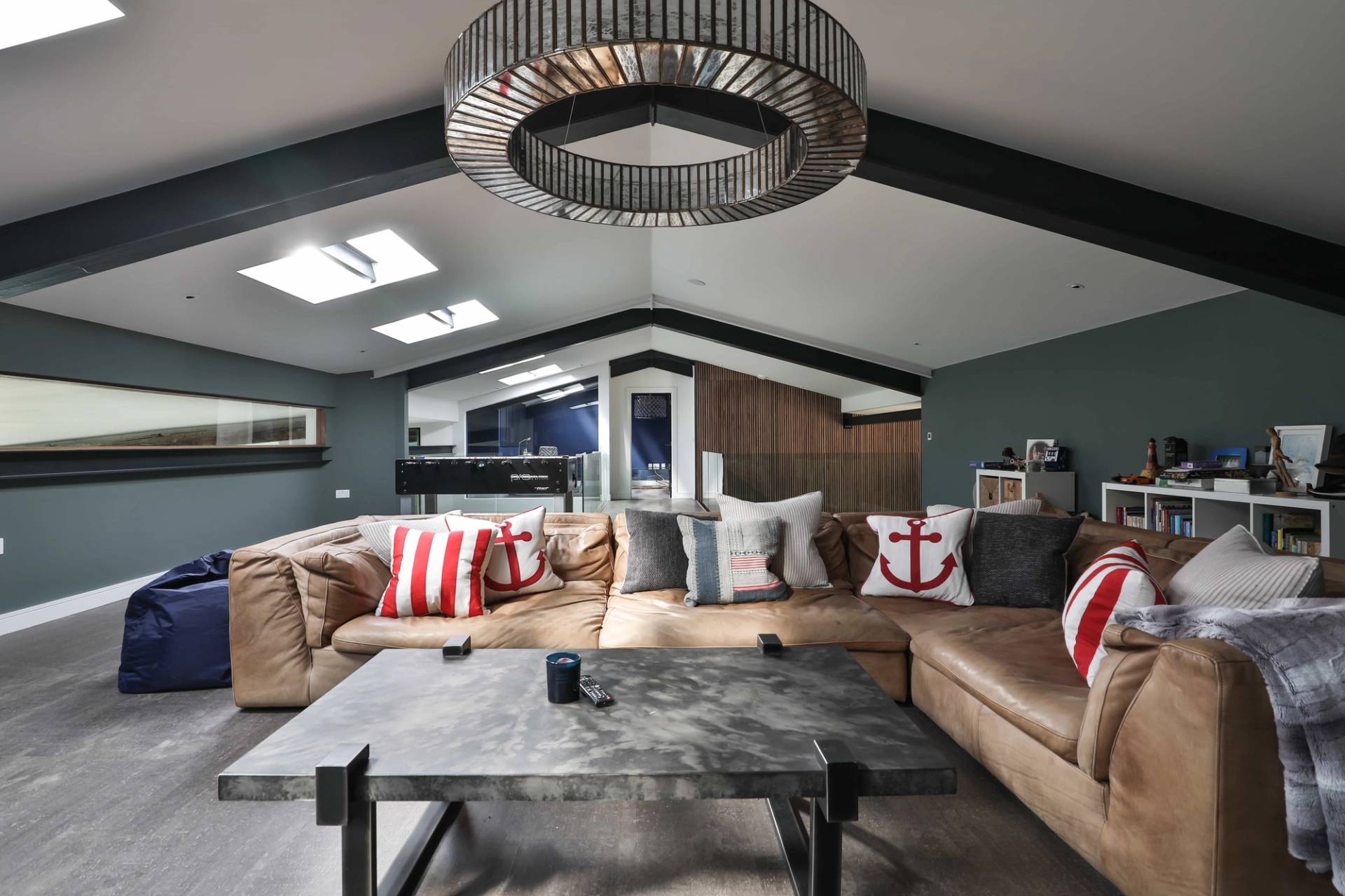Upper mezzanine family lounge featuring a tan leather sectional sofa, square coffee table, and roof skylights, Love Locations CV23.
