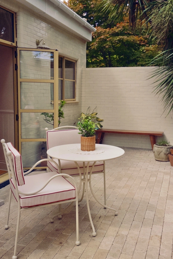 Charming exterior patio space featuring a white bistro set against a white brick wall, ideal for outdoor lifestyle brand campaigns, Love Locations Hounslow.