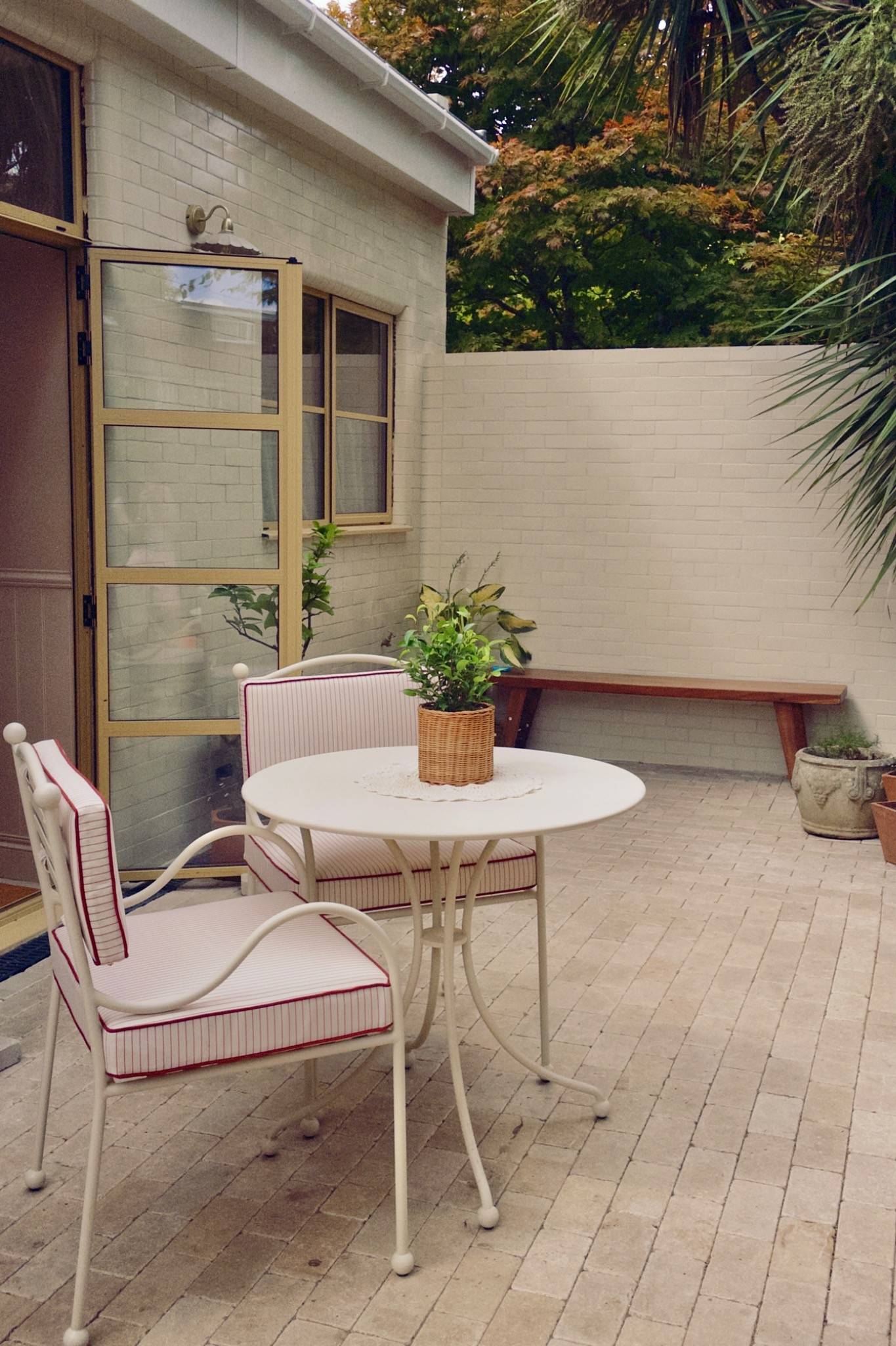 Charming exterior patio space featuring a white bistro set against a white brick wall, ideal for outdoor lifestyle brand campaigns, Love Locations Hounslow.