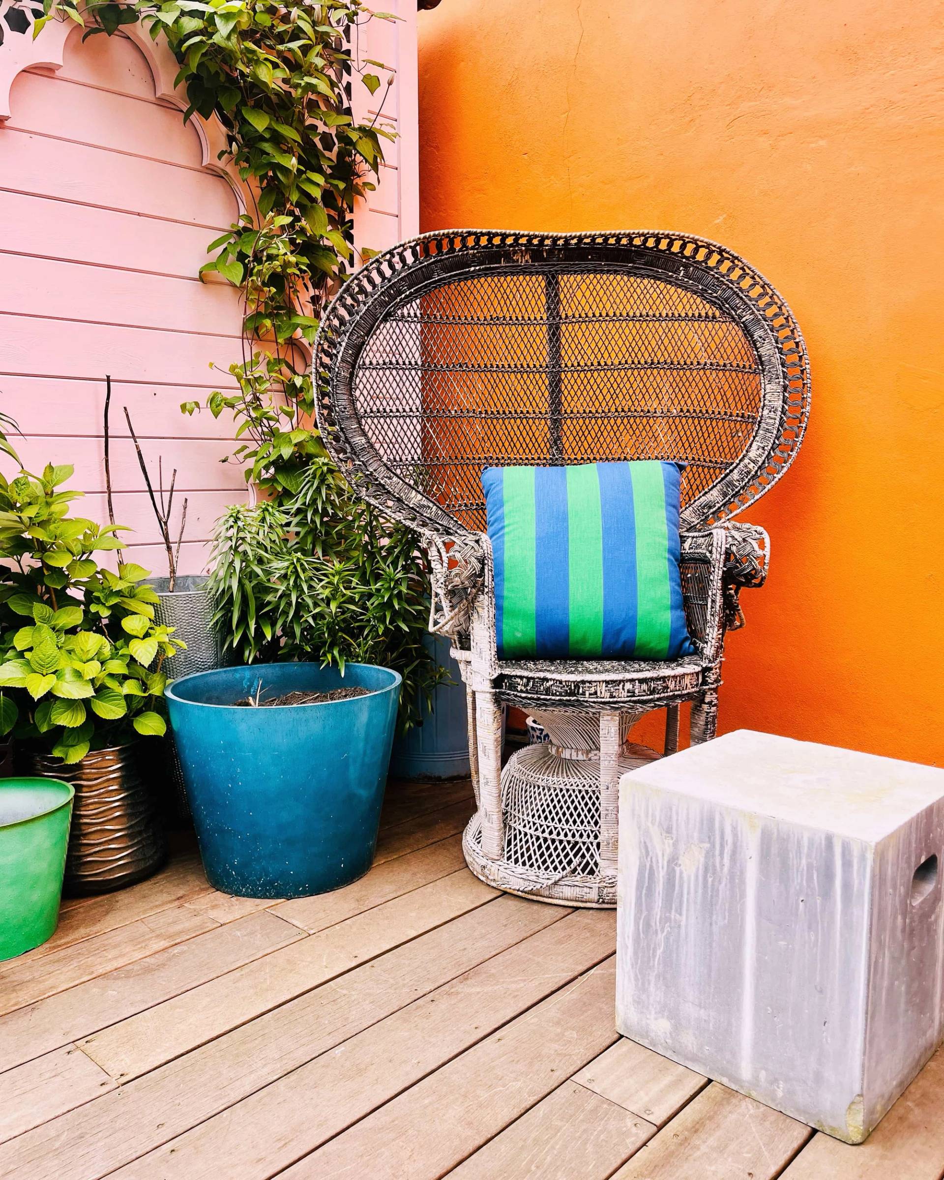 Wicker peacock chair set on a timber deck against an orange exterior wall, Love Locations SE6.