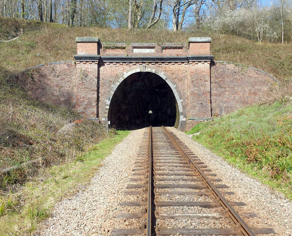 Historic brick railway tunnel portal entrance framed by stone arches and single track rail lines, ideal for cinematic film scenes, Love Locations.