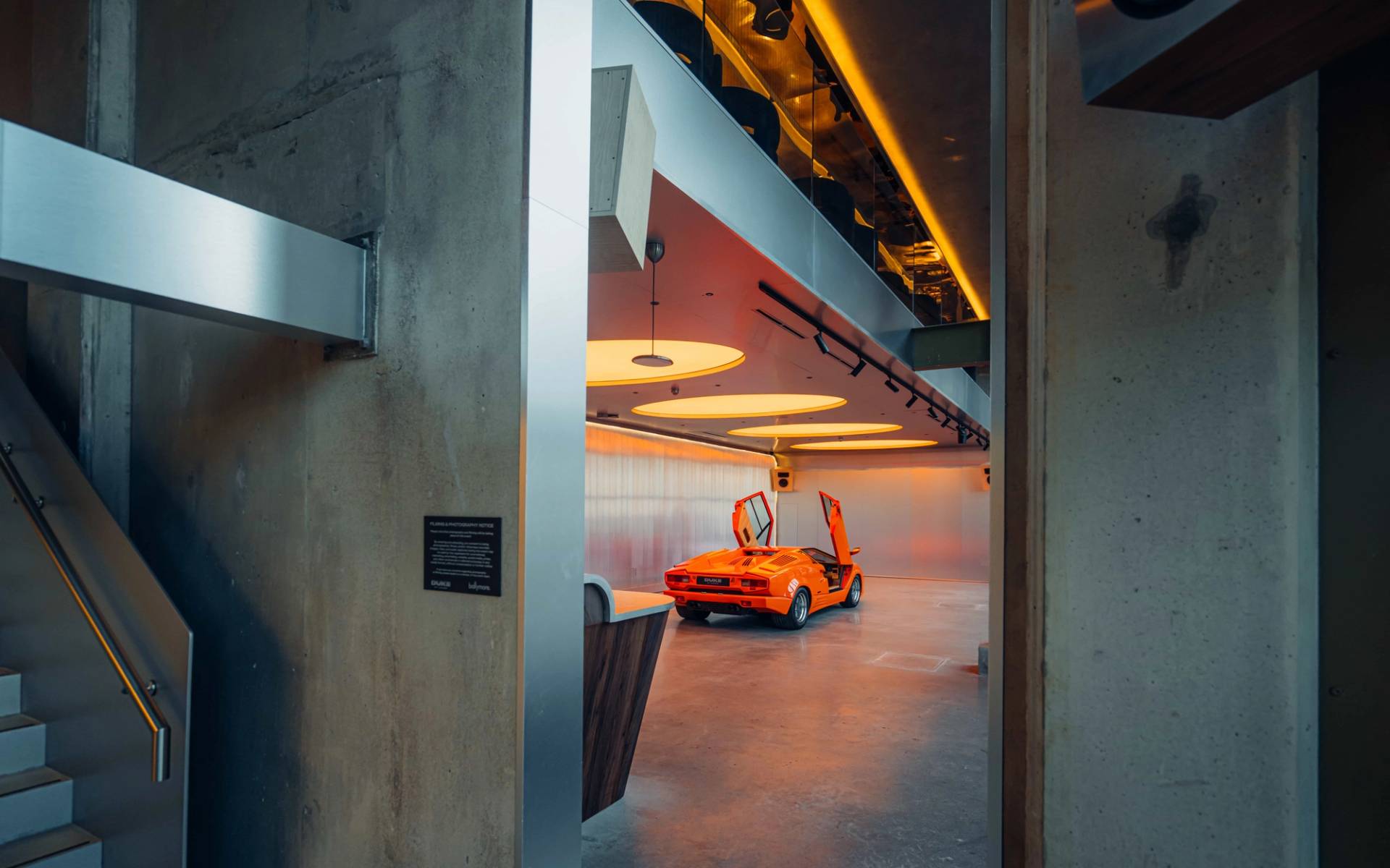 Concrete pillar view framing an orange Lambo in an audiophile listening bar location house in Brentford TW8 by Love Locations.