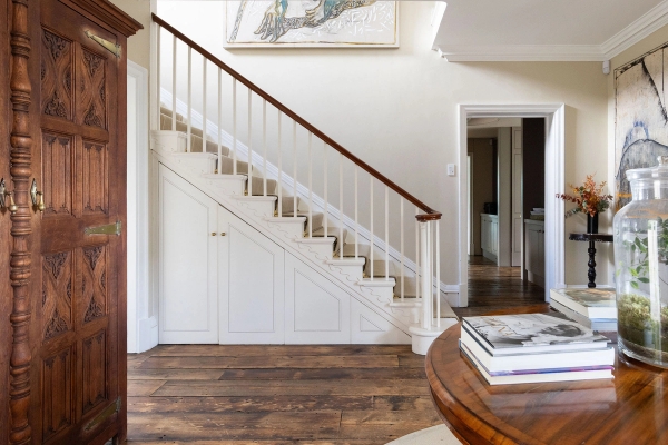 Love Locations period staircase film location West Sussex: Elegant white wooden balustrade banister over dark oak flooring, optimized for dramatic walking and tracking shots in television dramas.