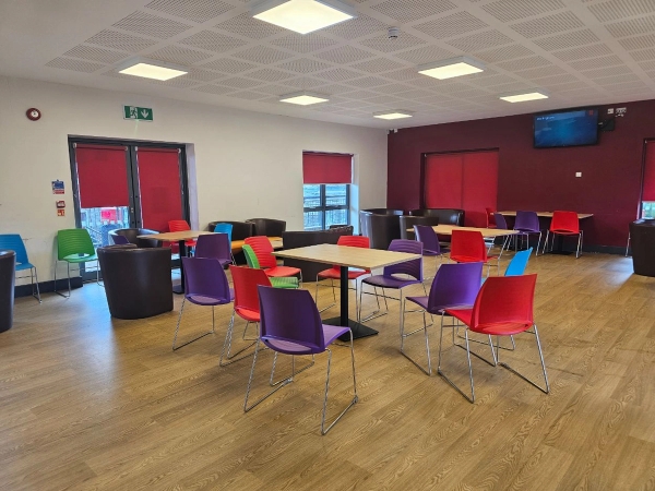 Bright secondary school dining hall setting with contemporary wooden flooring for television and commercial filming, listed by Love Locations.
