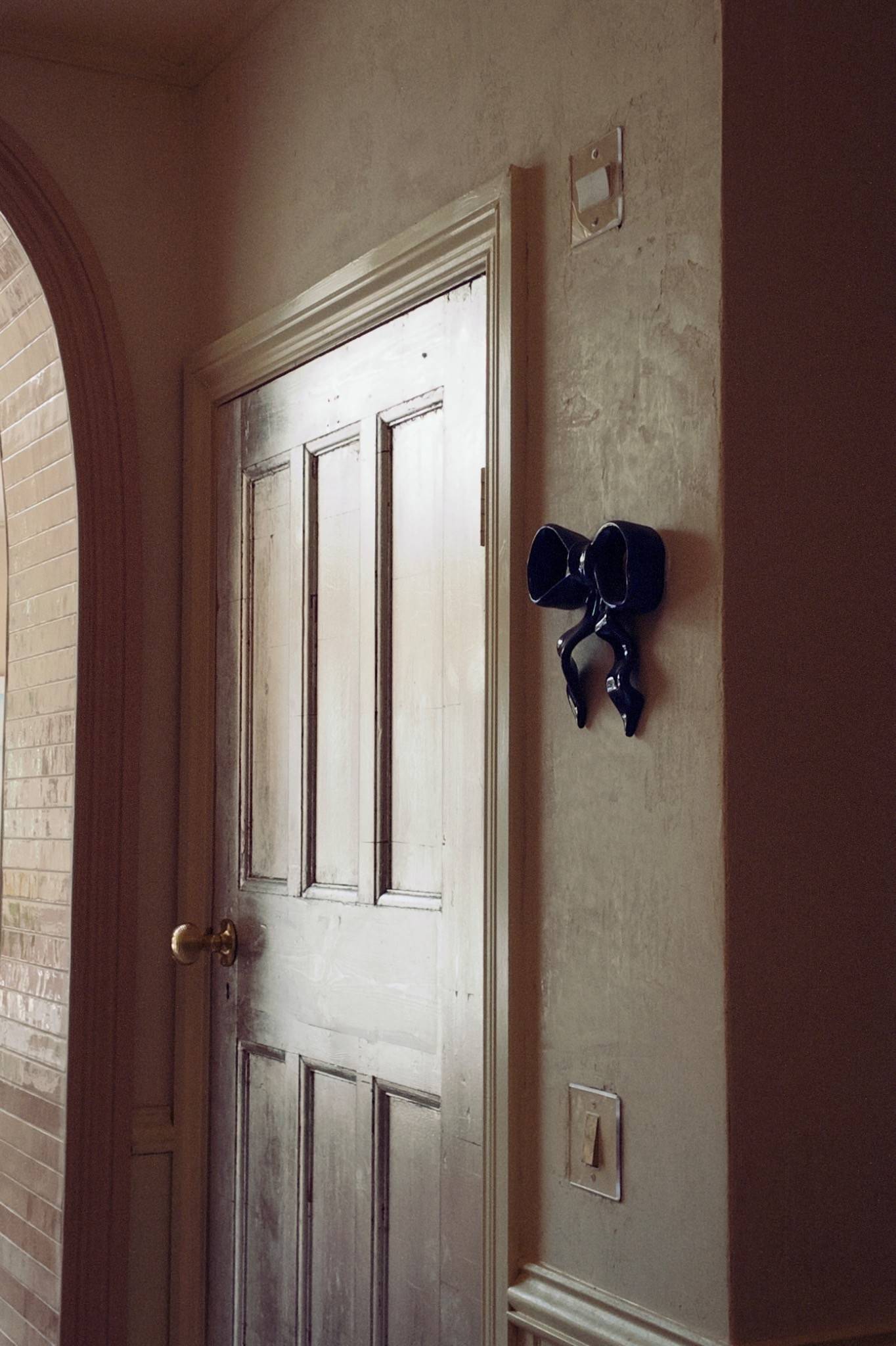 Distressed white panel interior door featuring dark decorative wall hooks in an Isleworth home, Love Locations West London.