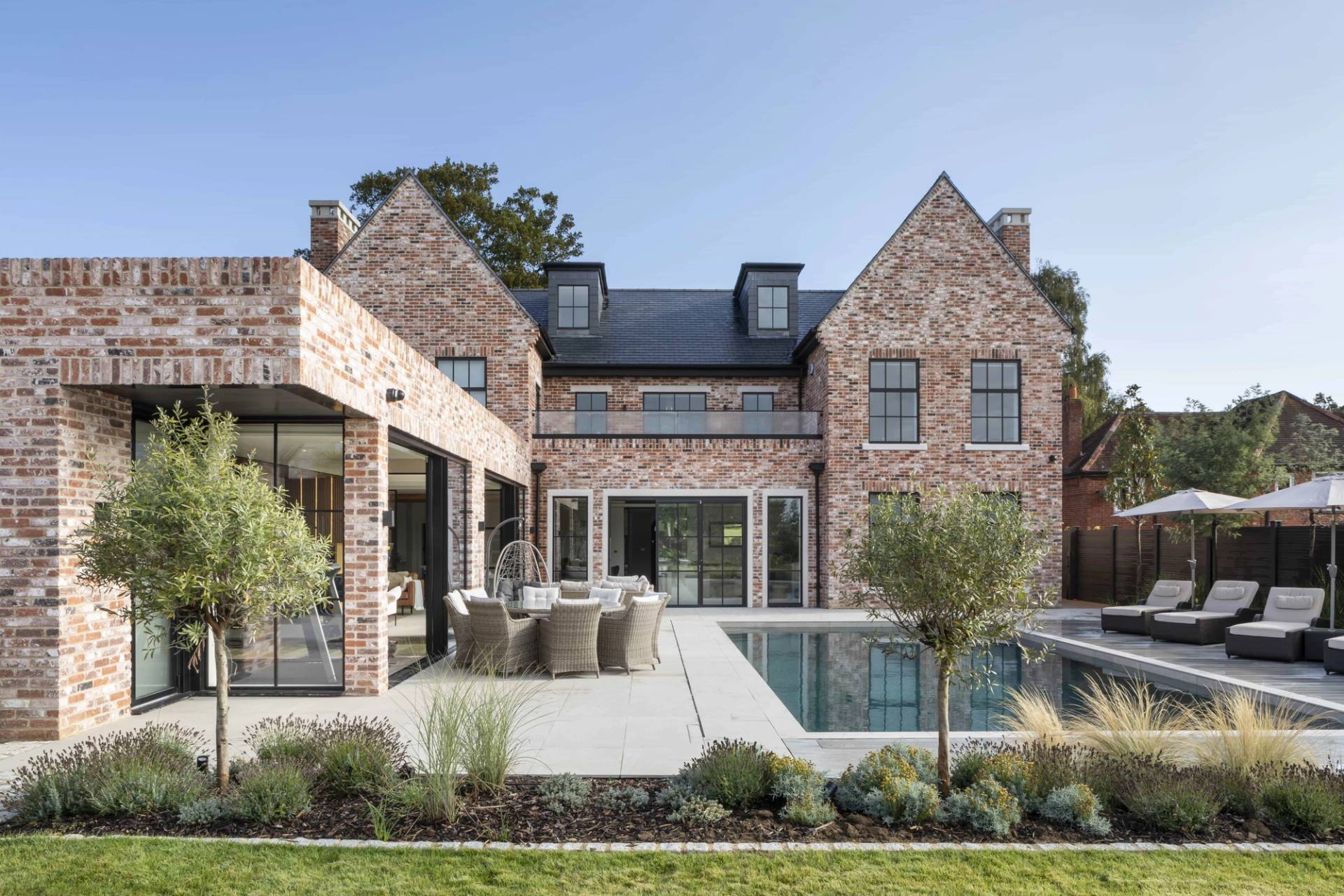 Wide-angle perspective of a brick mansion with swimming pool, paved patio, and manicured lawn grounds, Love Locations HP18.