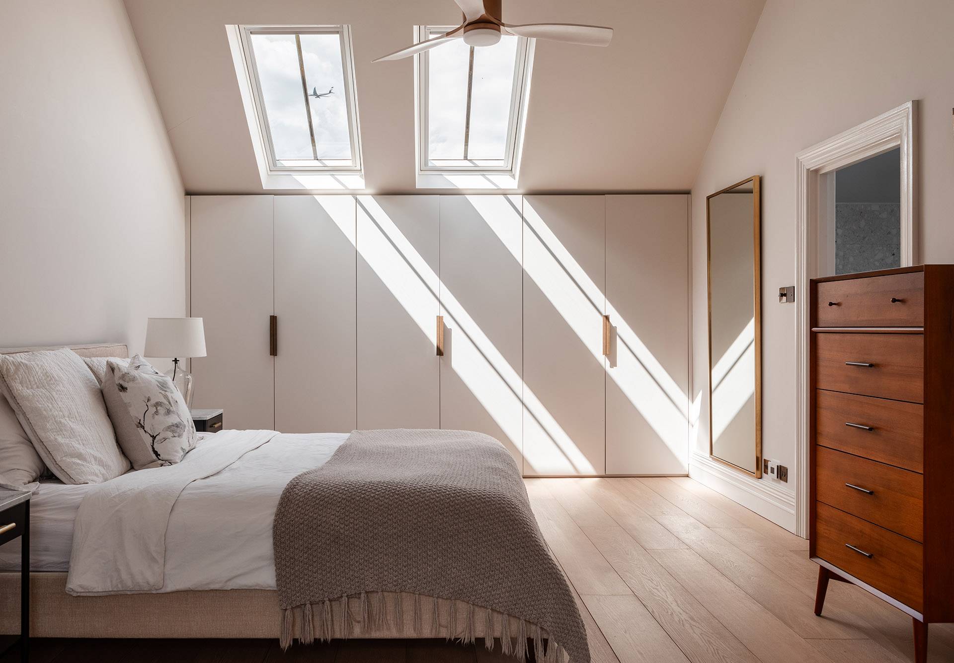 Sunlit top-floor bedroom showcase highlighting clean sloping ceilings and natural wood flooring, Love Locations.