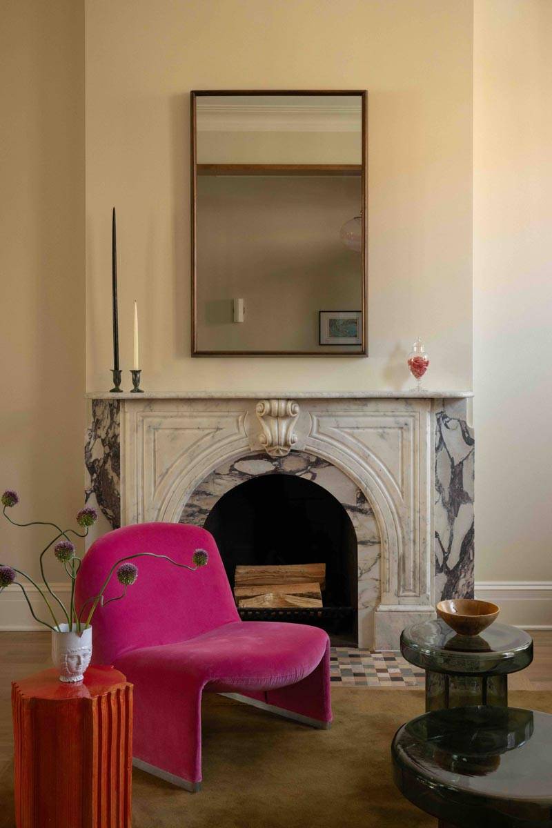 Classic period living room with a marble fireplace mantlepiece in a Boerum Hill townhouse Brooklyn NY 11217 from Love Locations, featuring a bold hot pink armchair and high ceilings.