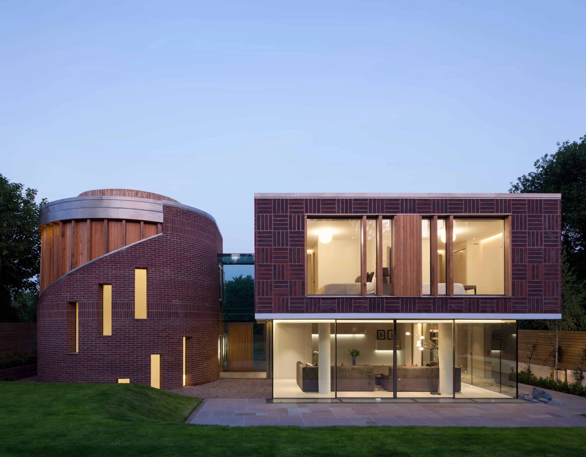 Contemporary red brick facade set under evening lighting with floor-to-ceiling glass windows, Love Locations WD7.