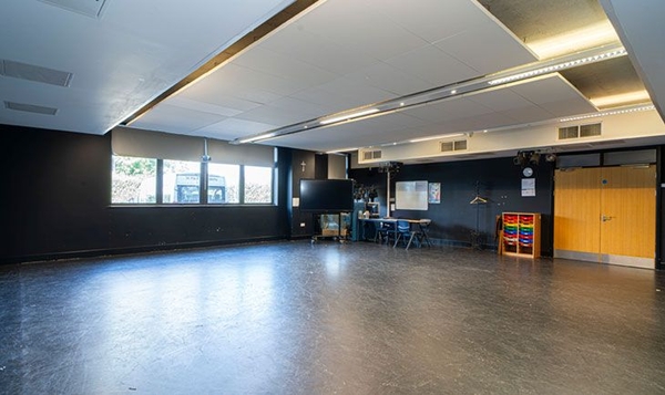 Love Locations empty drama studio location SE2: Spacious, clean activity room with deep grey walls and professional acoustics, perfect for actor interviews and stage performance shoots.