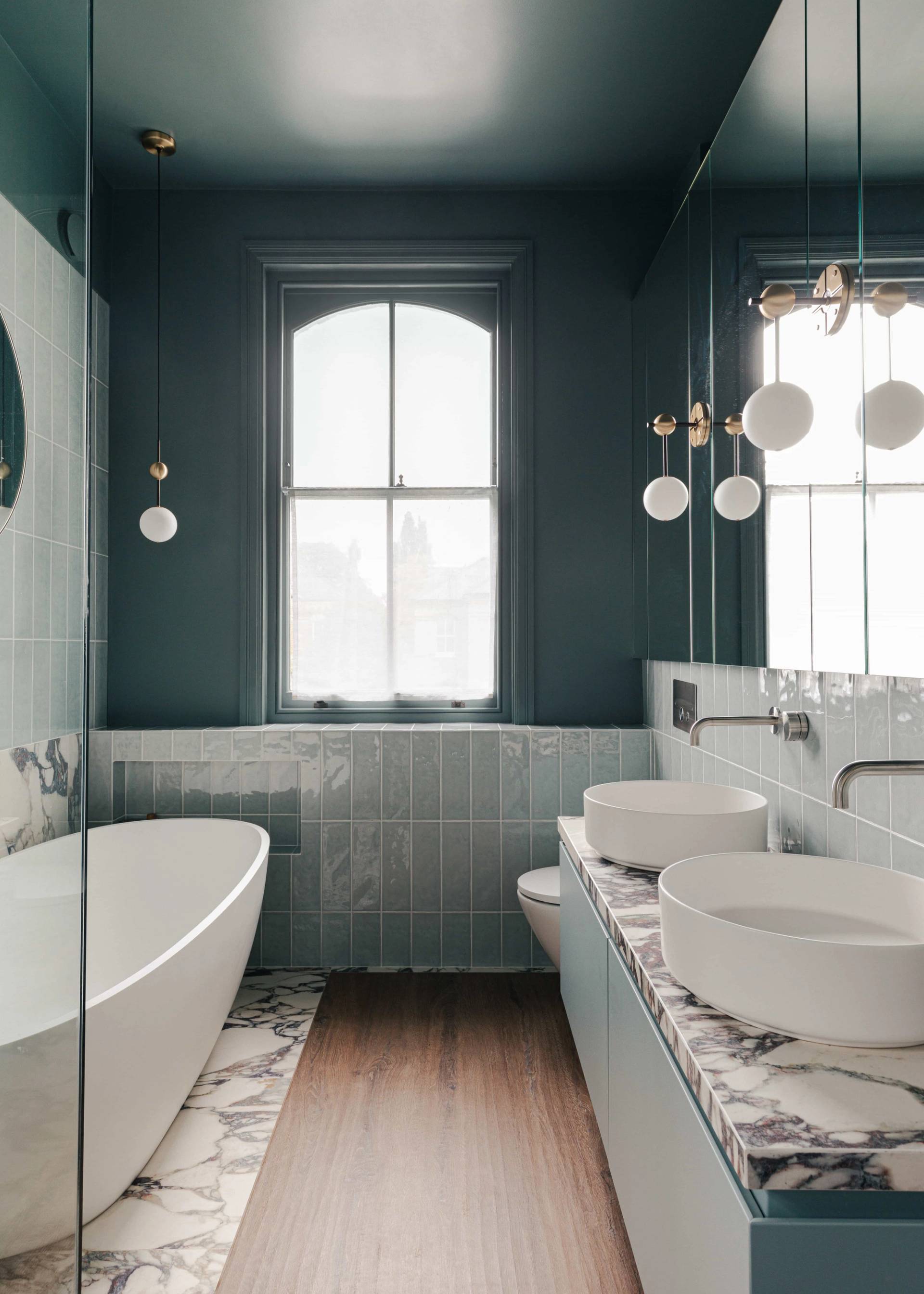 Luxury master bathroom featuring a white soaking tub, double vessel sinks, and dark teal walls, ideal for wellness product marketing, Love Locations SW13.