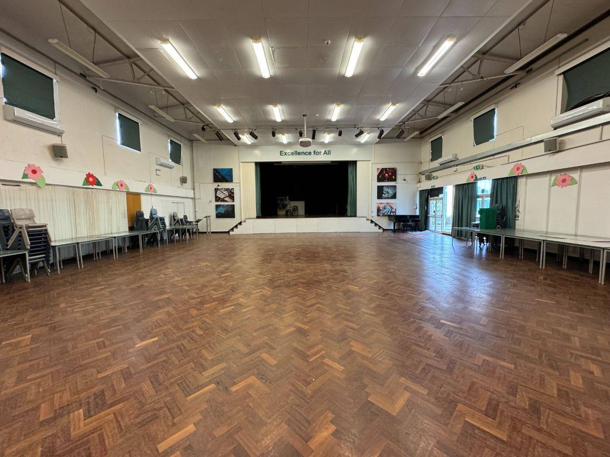 Traditional secondary school assembly hall film location in North Finchley Barnet N12 from Love Locations, featuring polished parquet wood flooring and an elevated performance stage.
