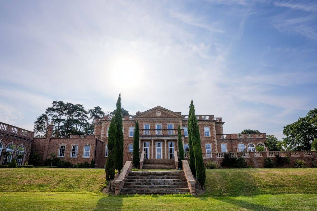 Grand stone steps framed by manicured cypress trees leading up to the main house entrance, featured on Love Locations.