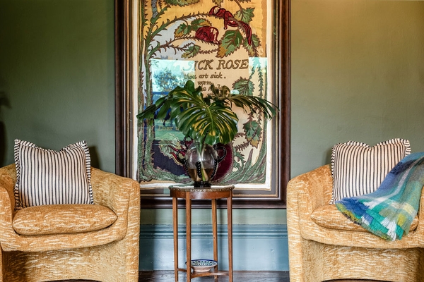 Symmetrical seating area vignette showcasing twin mustard yellow patterned armchairs flanking a vintage end table from Love Locations.