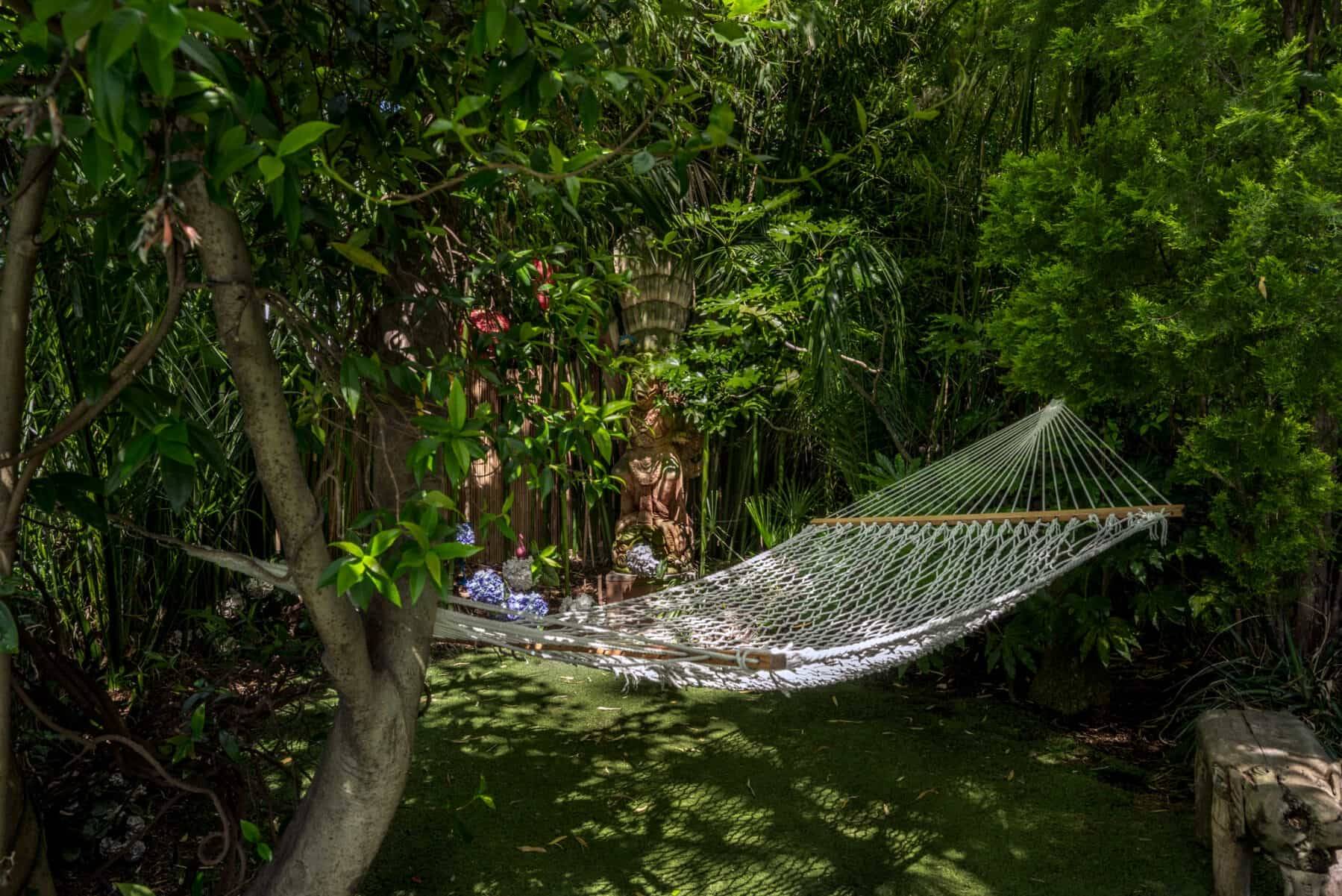 Woven rope hammock strung between mature trees in a private secluded garden in West London, Love Locations.