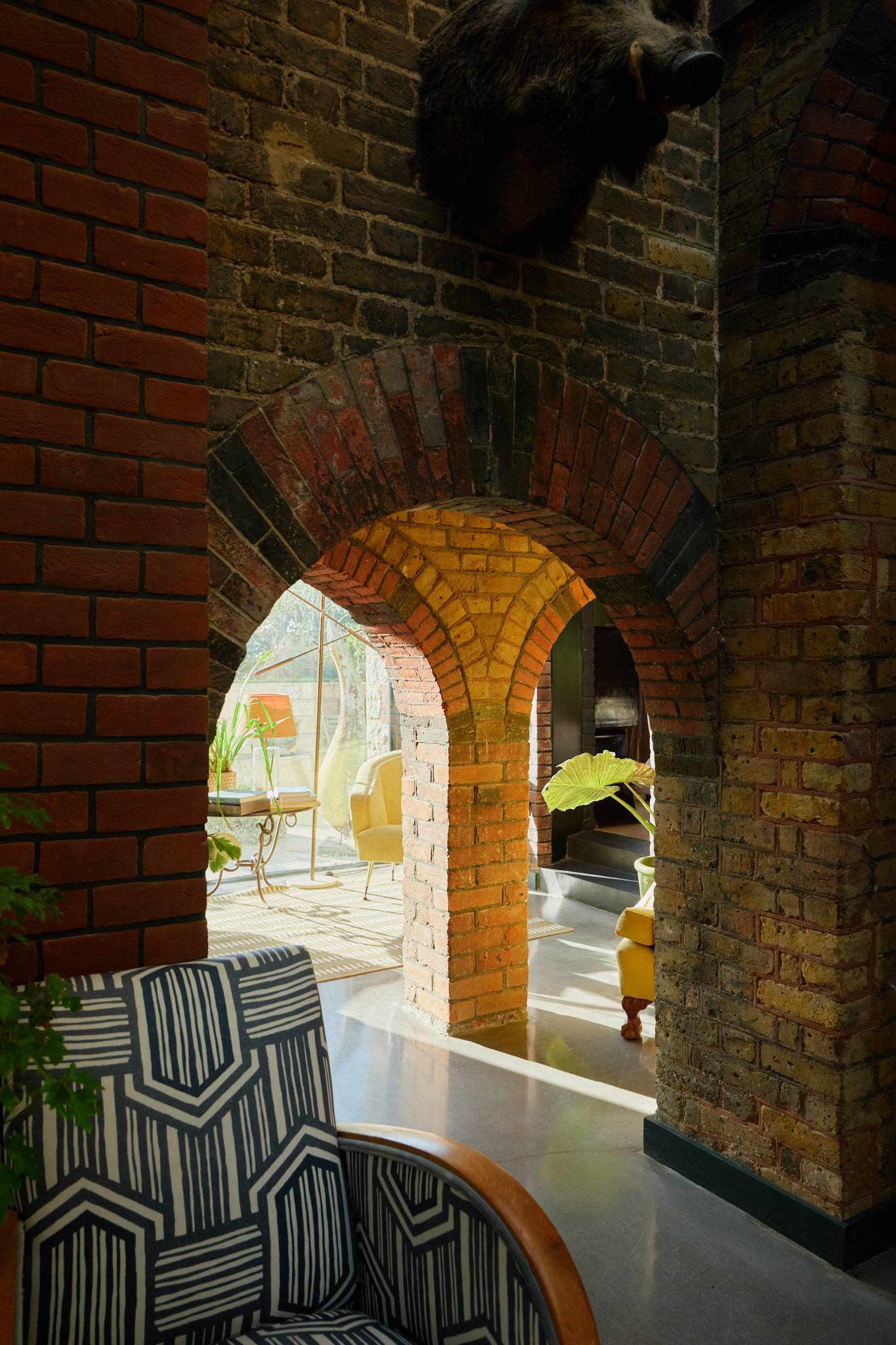 Historic brick arched walkway leading into a bright garden-view lounge in a Wimbledon location house, Love Locations.