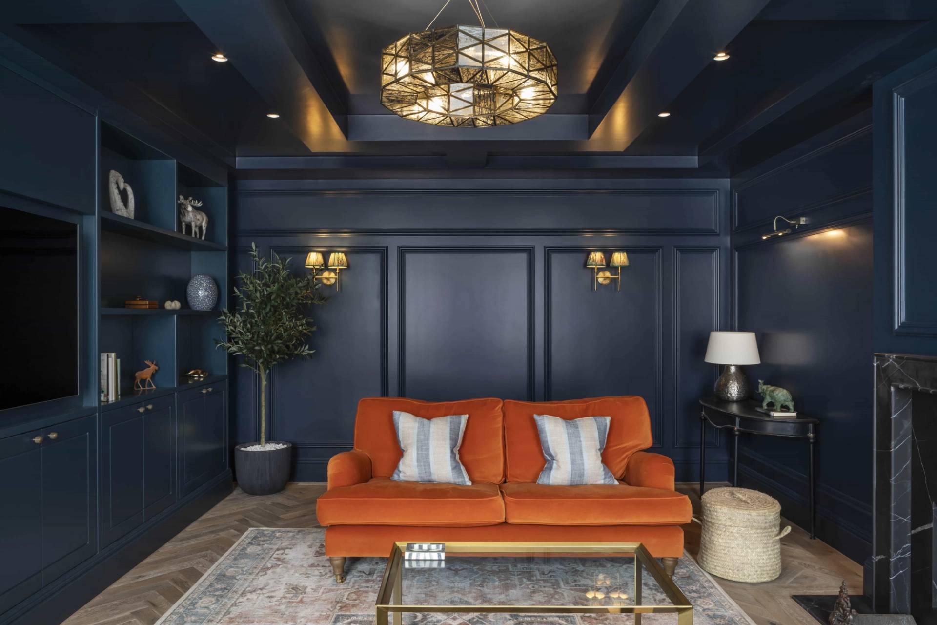 Luxury navy blue reception room set with an orange sofa, gold coffee table, and dark ceiling moldings, Love Locations HP18.
