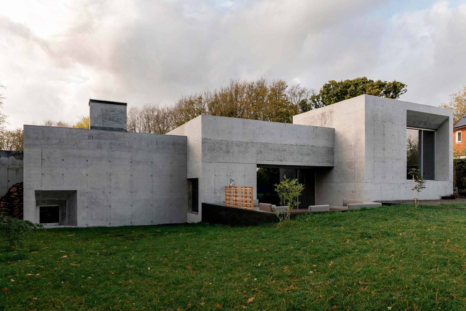 Brutalists board-marked concrete house exterior facade set in a vast green lawn garden in Plumpton Green, Love Locations BN7.