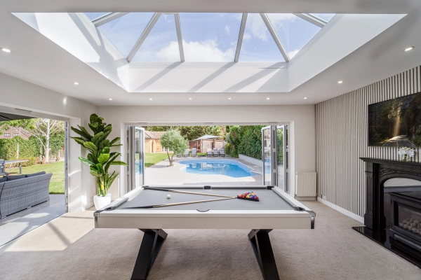 Games room pool table set in front of bi-folding glass doors opening directly to an outdoor pool terrace, Love Locations RM11.